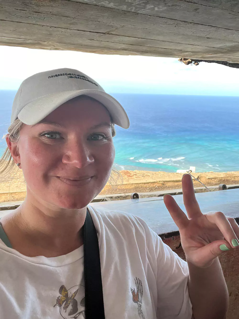 Katie taking a selfie near the summit of Diamond Head, with the historic concrete pillbox bunker behind her and sweeping ocean views in the distance.
