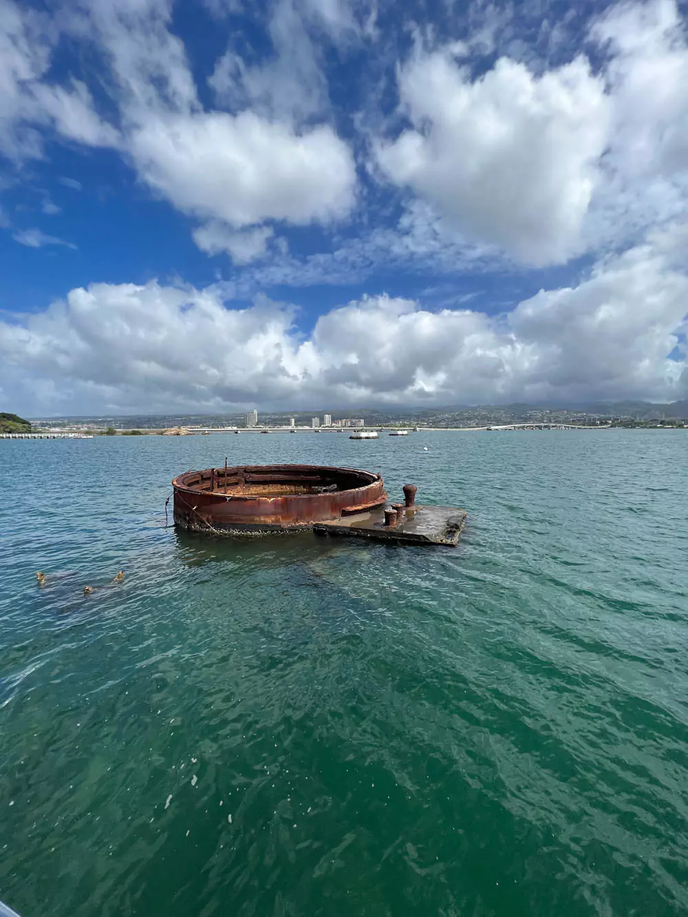 Remains of Turret 3 from the USS Arizona visible above the water at Pearl Harbor, marking part of the sunken battleship and honoring those lost in the 1941 attack.