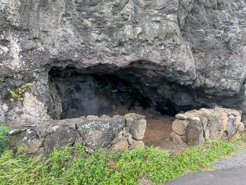 Cliffside filming location from Triple Frontier at Kualoa Ranch, featuring steep, green-covered rock faces overlooking dense jungle valleys, as seen in the dramatic helicopter escape scene.