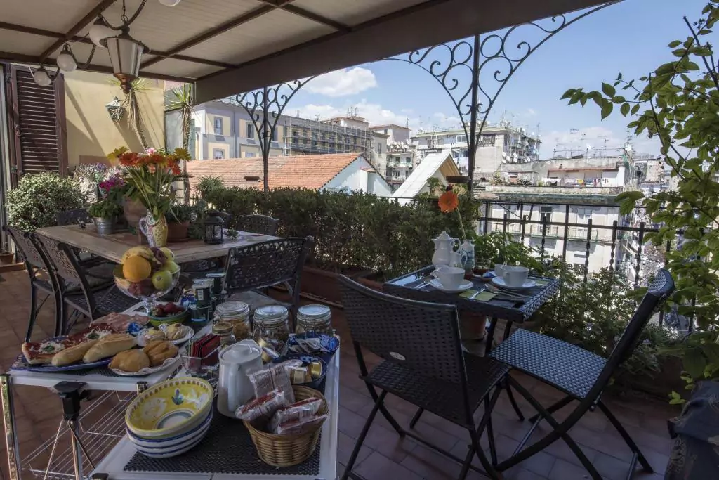 Terrace at Terrazza Duomo featuring a dining table set for a meal, surrounded by elegant chairs and overlooking rooftops and cathedral spires