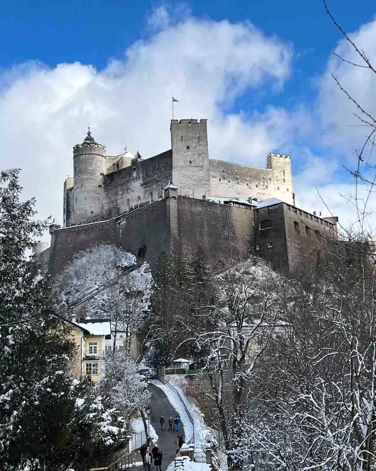 Hohensalzburg Fortress perched atop Festungsberg hill, overlooking the city of Salzburg, Austria, with its medieval stone walls and towers dominating the skyline above the baroque Old Town.