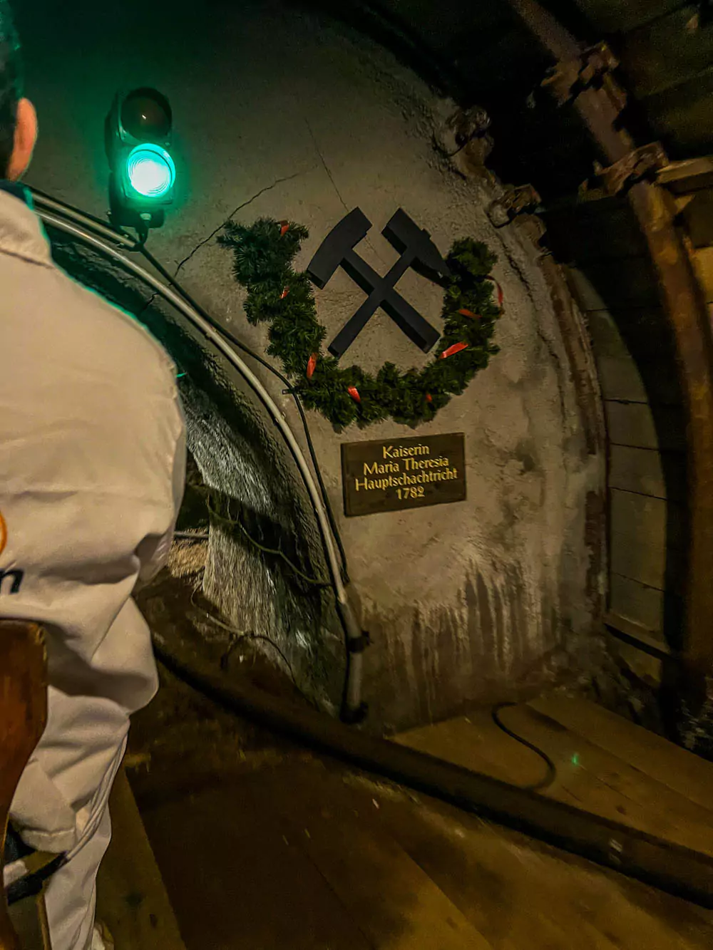 Mine train departing from the Kaiserin tunnel at Hallstatt Salt Mine (Salzwelten), with the narrow track leading into a salt-carved passageway. The low-lit scene highlights the historic transport system once used by miners.
