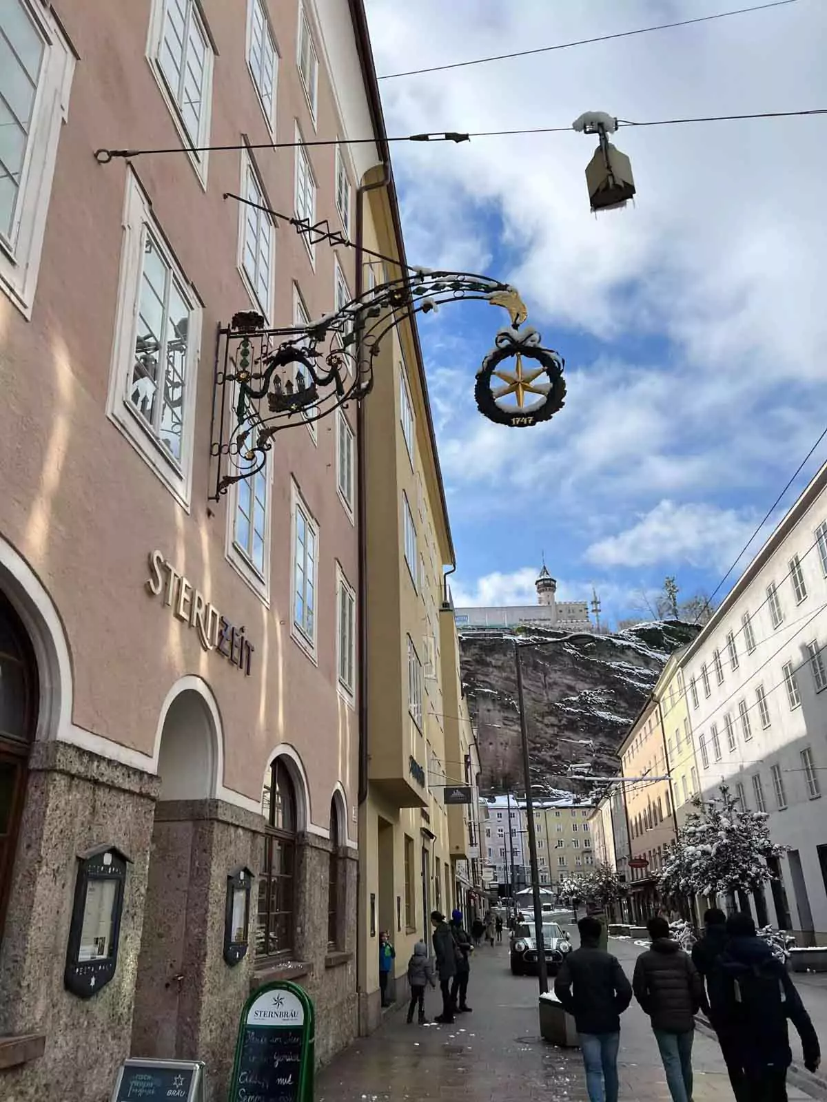Entrance to Sternzeit in Salzburg’s Old Town, Austria, featuring a warmly lit doorway nestled between historic stone buildings, with traditional signage and charming architectural details.