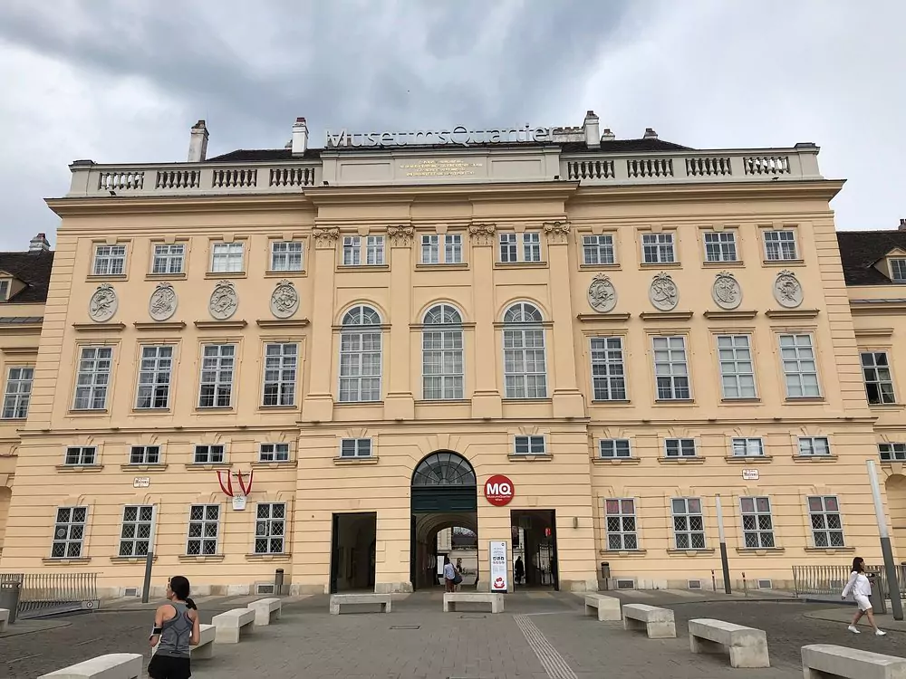MuseumsQuartier in Vienna, Austria, a large cultural complex featuring contemporary and historic buildings, open courtyards with seating, and visitors enjoying art museums, events, and cafés in a lively atmosphere.