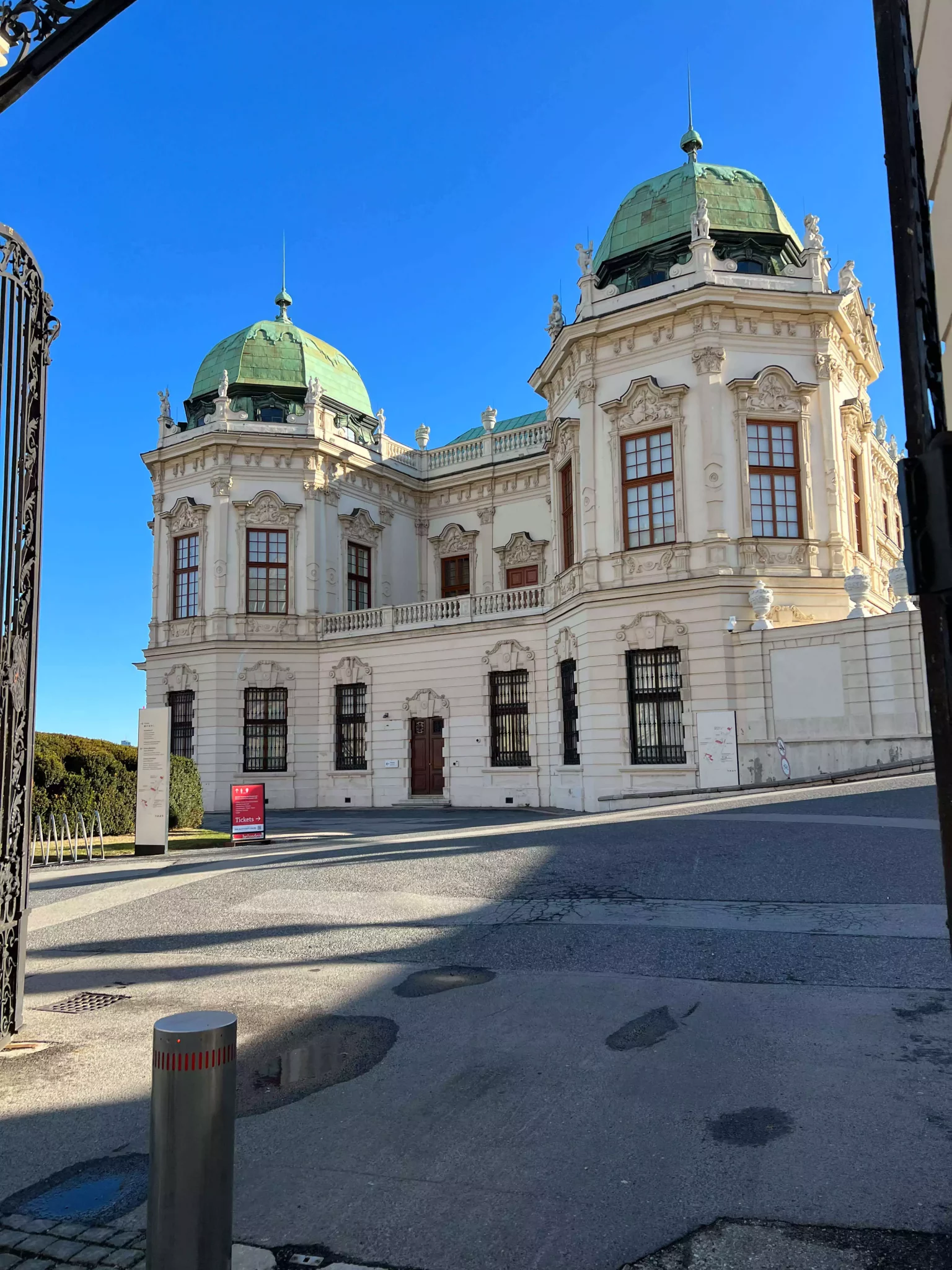 Schloss Belvedere in Vienna, Austria, a grand Baroque palace complex with ornate white façades, green copper domes, and symmetrical gardens in the foreground, housing a renowned art collection including works by Gustav Klimt.