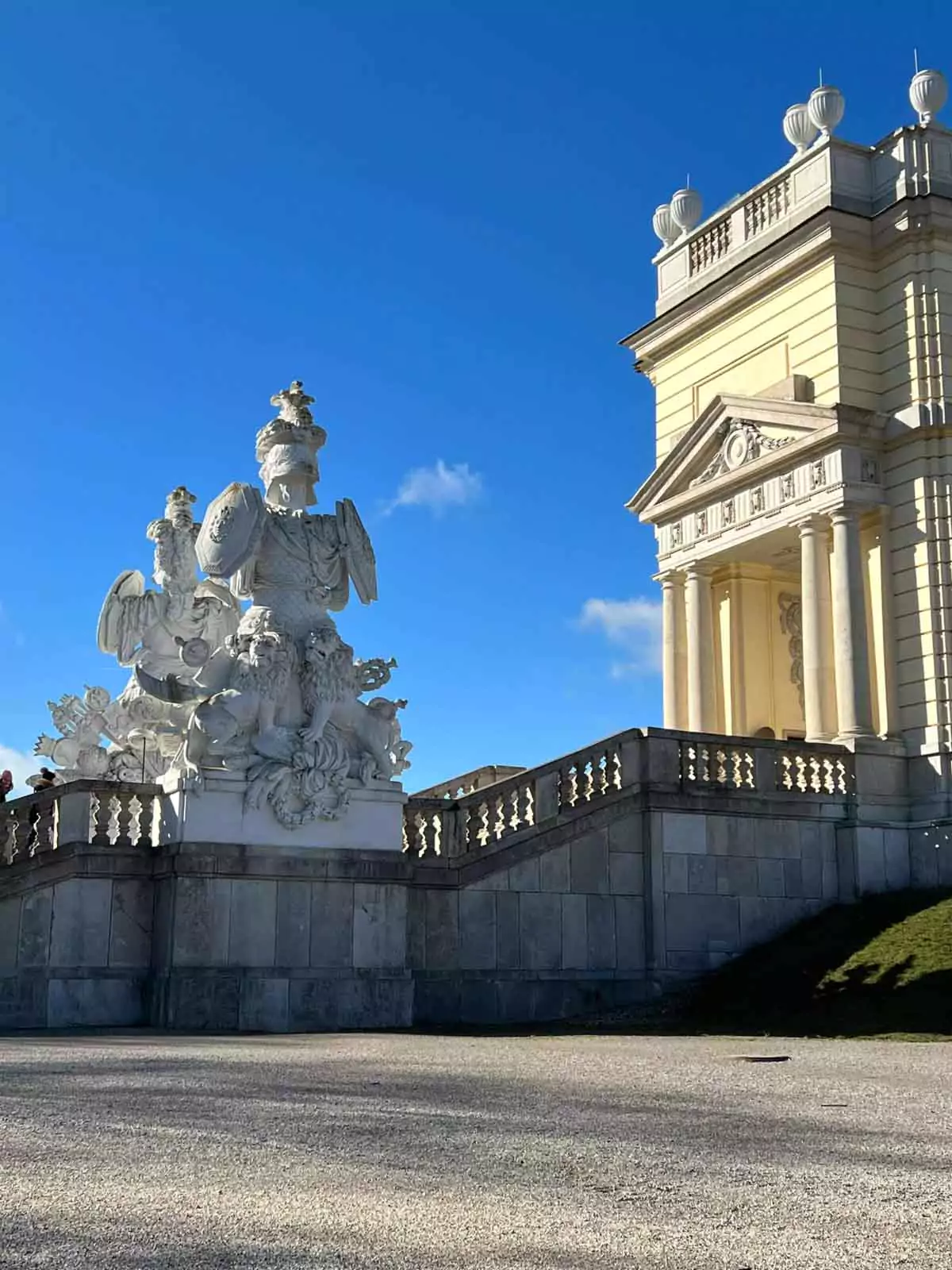 Statue on the staircase of the Gloriette at Schönbrunn Palace in Vienna, Austria, depicting a classical figure in white stone, overlooking the gardens and offering a regal accent to the grand Baroque structure.