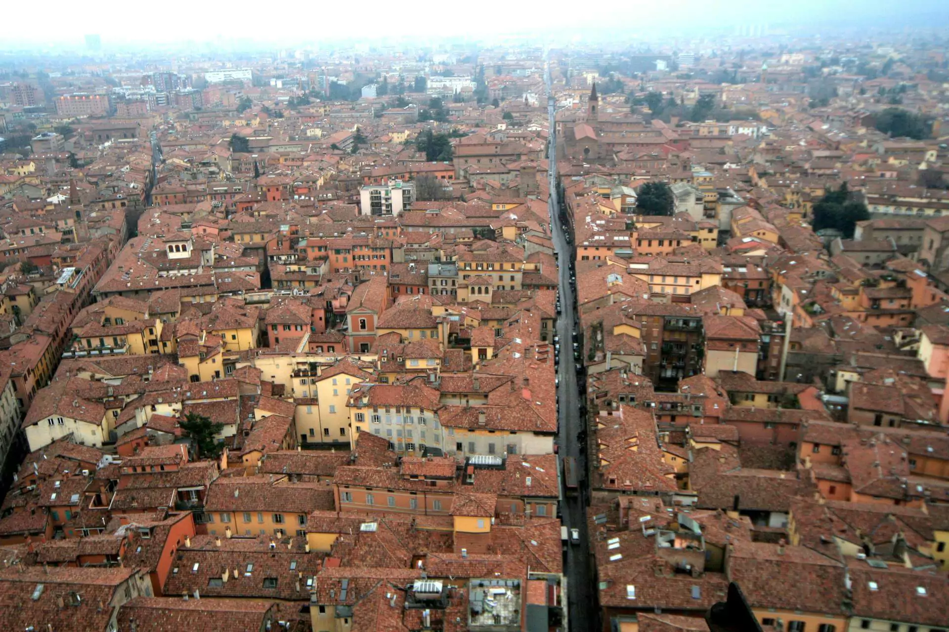 Panoramic view of Bologna, Italy, featuring the iconic red-tiled rooftops, medieval towers, and the historic Two Towers (Due Torri) under a clear blue sky — a classic scene capturing the charm of Bologna, Italy.