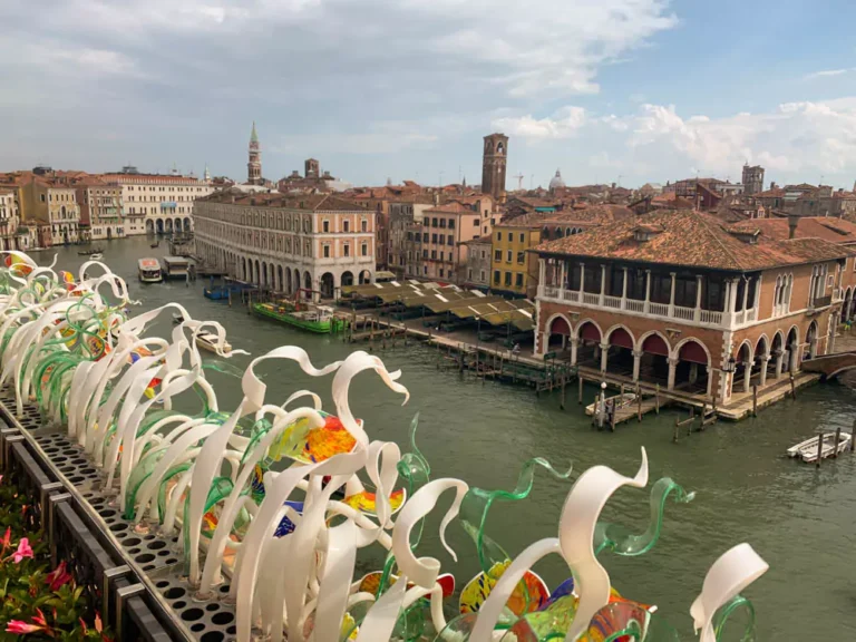 Rooftop view from Ca’ Sagredo Hotel in Venice, Italy, overlooking the Grand Canal with passing gondolas and historic palazzos lining the waterway under a soft Venetian sky.