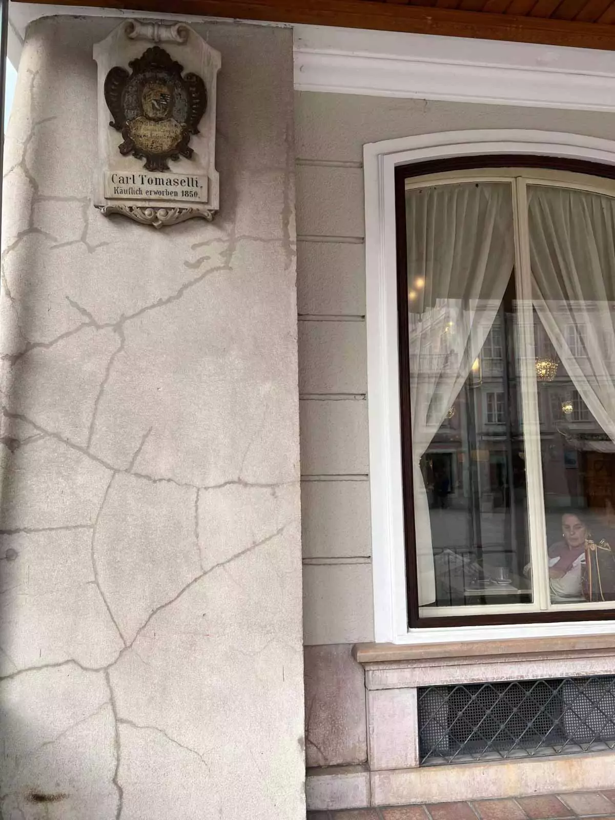Café Tomaselli sign mounted on the exterior of a historic building in Vienna, Austria, featuring elegant script lettering and classic European café charm.