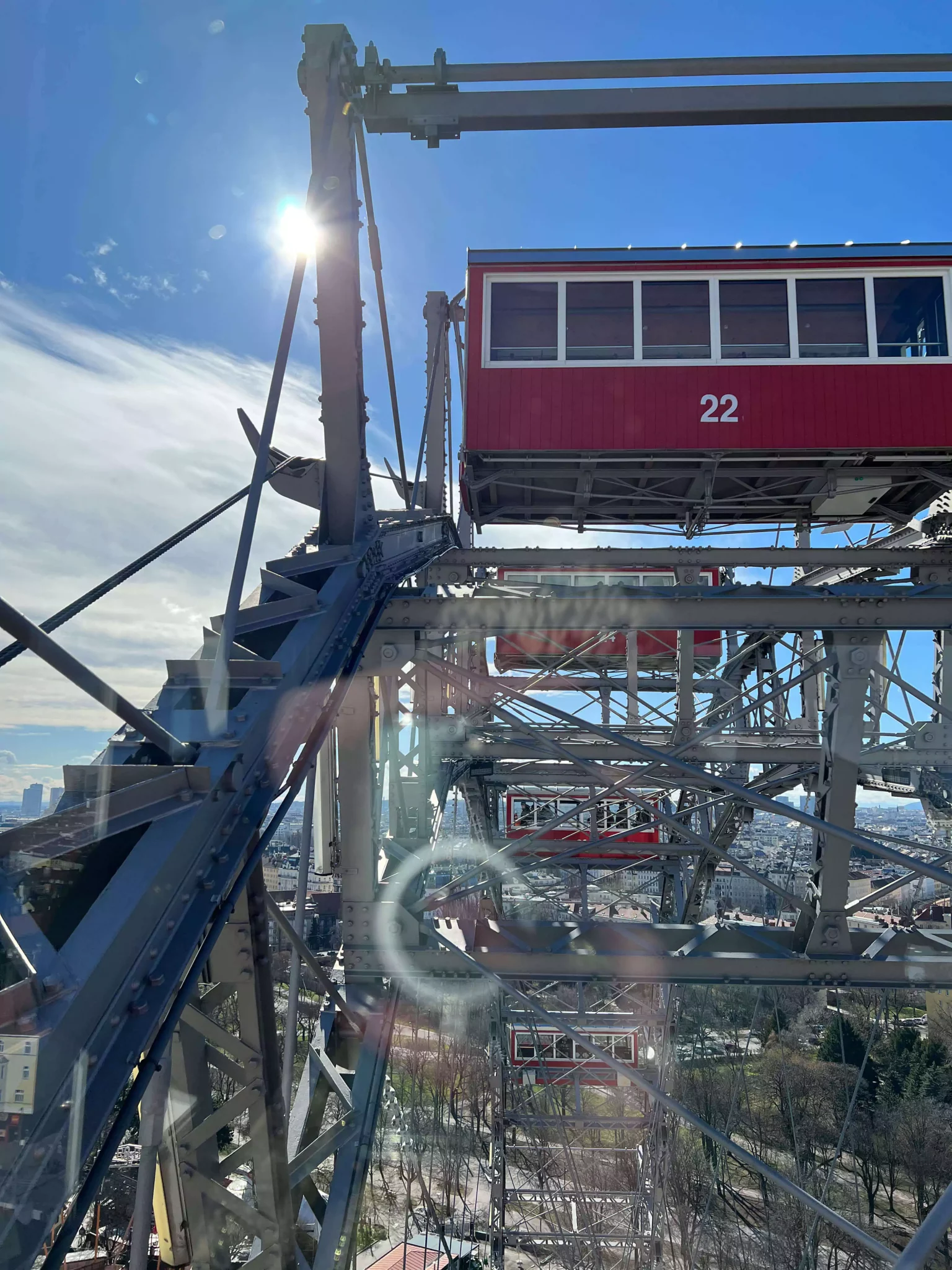 Cart 22 on the giant Ferris wheel at Prater in Vienna, Austria, painted in the iconic red with white numbering. The vintage-style cabin contrasts against the steel frame, capturing the charm of this historic amusement ride.