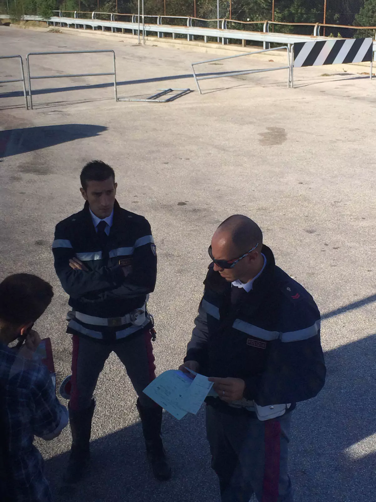 Contiki tour bus pulled over by Italian police on the roadside, with officers speaking to the driver near a highway or rural setting in Italy during a group travel journey.
