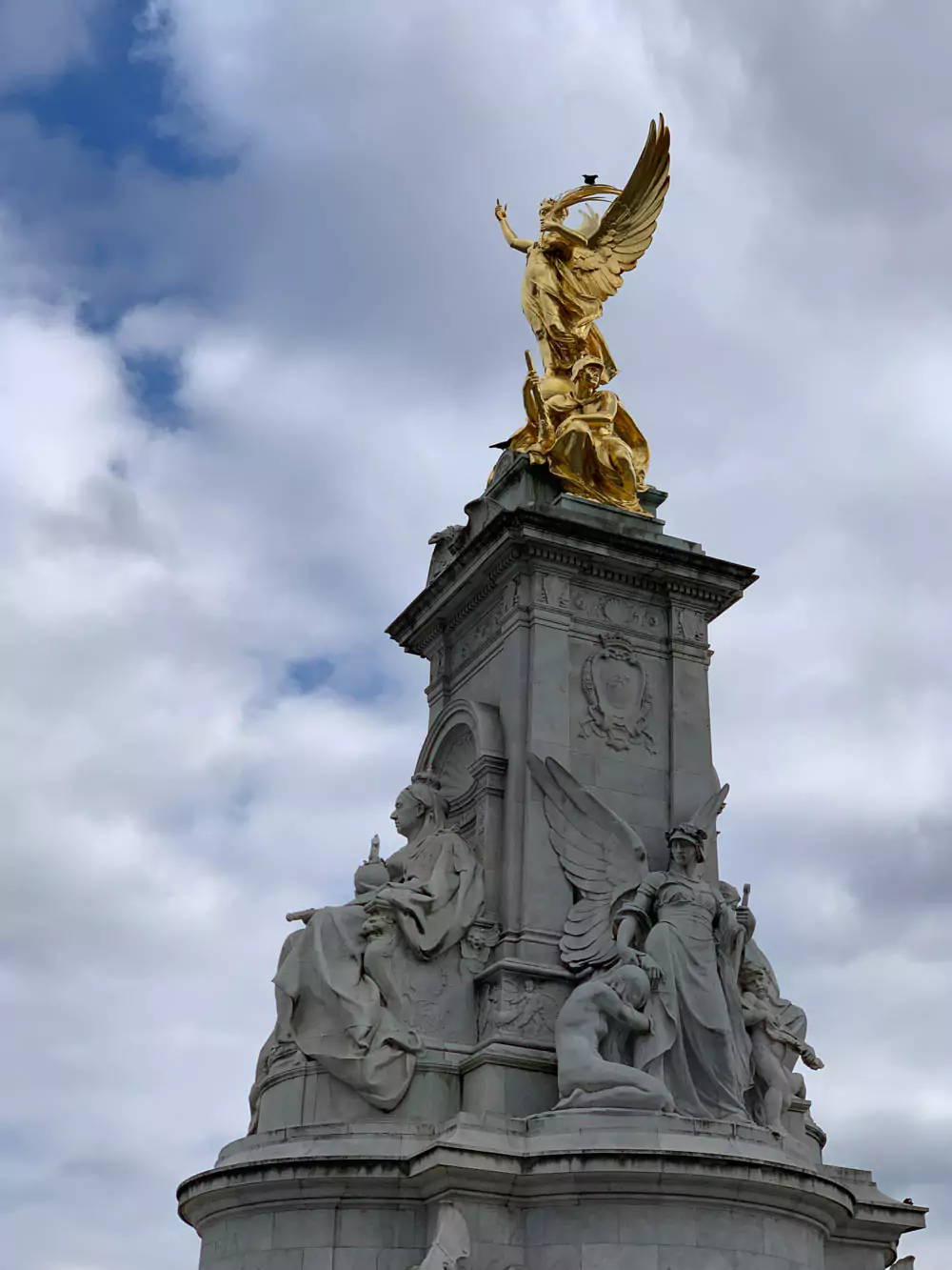 Queen Victoria Memorial in front of Buckingham Palace in London, England, featuring the grand white marble monument topped with a golden statue. The palace’s iconic facade provides a royal backdrop, drawing visitors to this historic ceremonial site.
