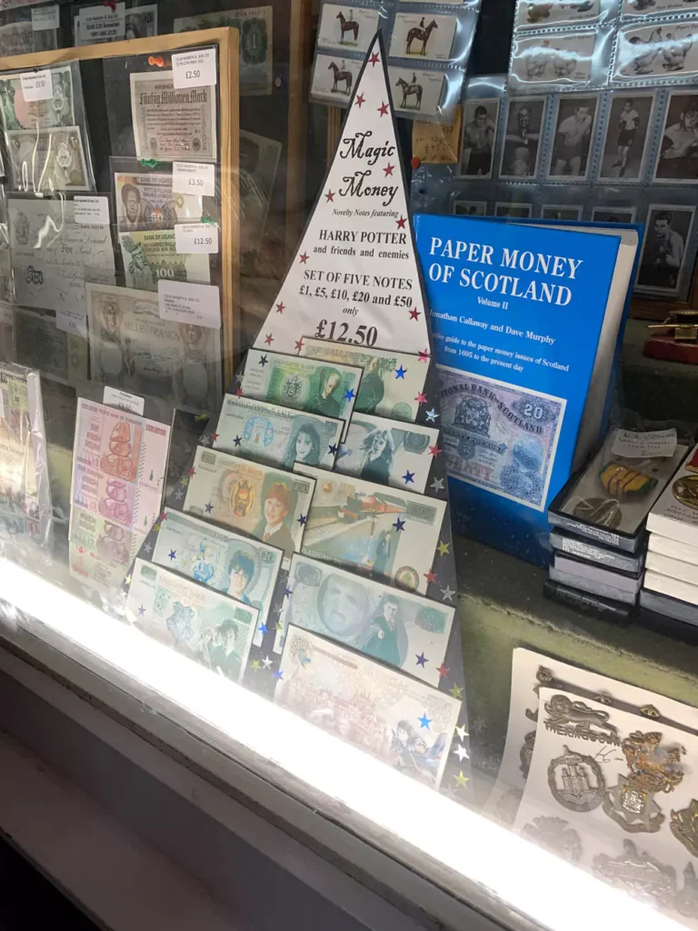 A shop window in London displaying magical currency labeled ‘Magic Money,’ with gold coins and wizard-themed decorations referencing the Harry Potter universe. The festive display captures the fantasy world’s enchanting atmosphere for fans and visitors.