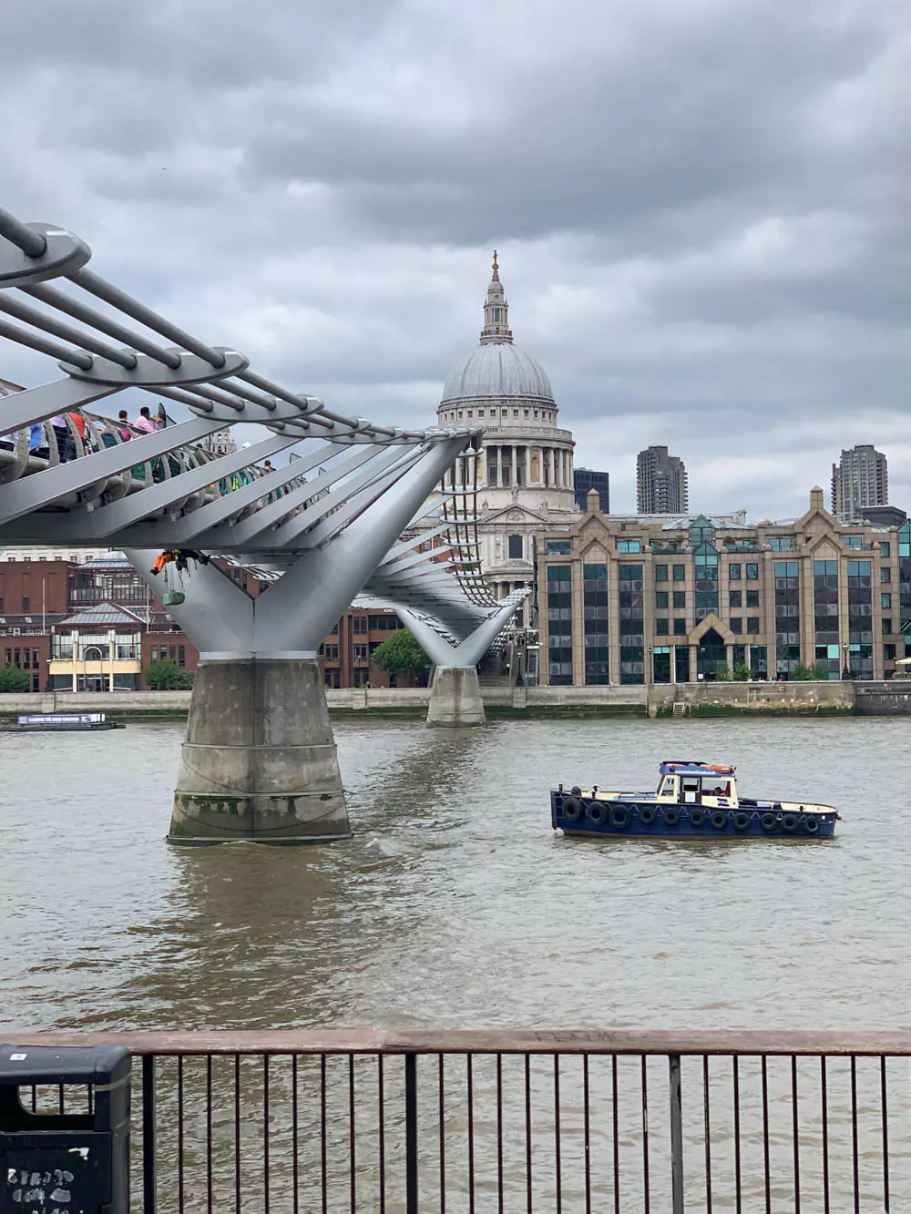 View of St. Paul’s Cathedral in London with the sleek, modern Millennium Bridge stretching across the River Thames in the foreground. The contrast between the cathedral’s grand dome and the steel suspension footbridge highlights the city’s blend of historic and contemporary architecture. Millennium Bridge (The Half-Blood Prince)