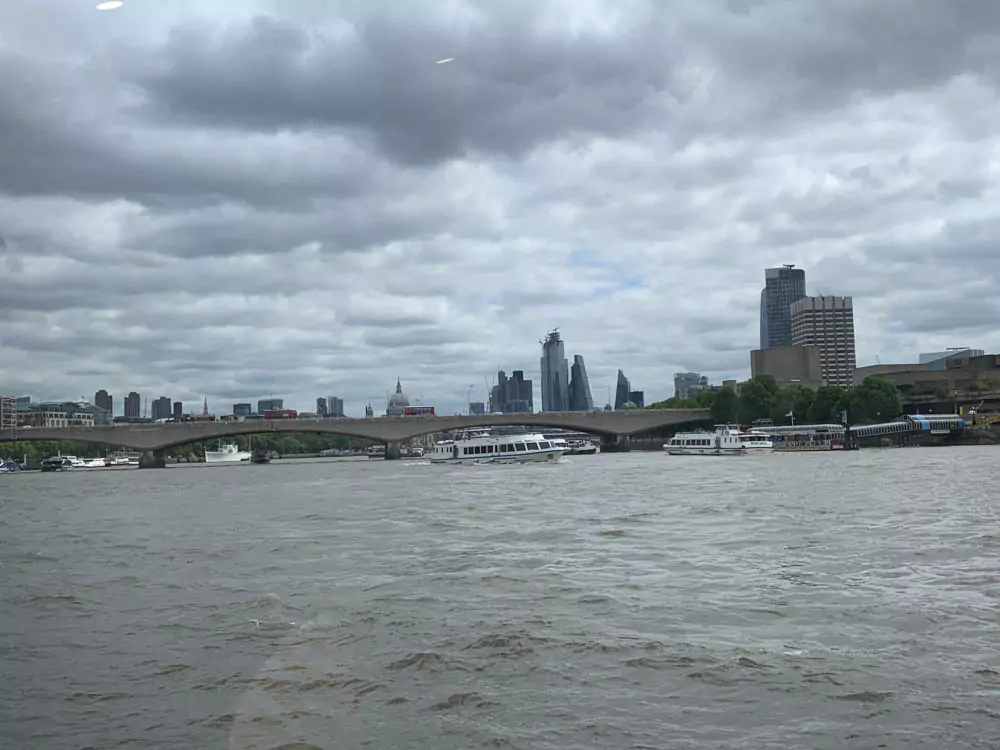 Panoramic view of London with the River Thames winding through the city, showcasing iconic landmarks like the London Eye, Tower Bridge, and modern skyscrapers. The mix of historic and contemporary architecture reflects the dynamic character of the city.