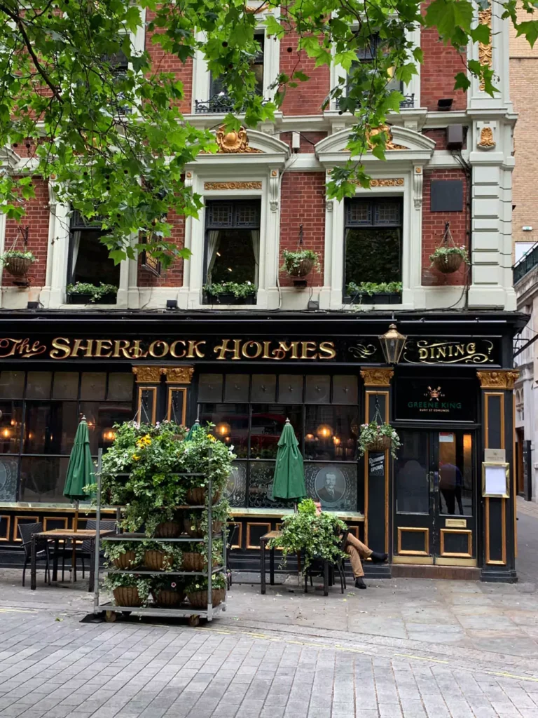 Exterior of the Sherlock Holmes Bar in London, featuring vintage signage, hanging flower baskets, and a classic pub facade. The cozy, themed atmosphere pays tribute to the famous detective with Victorian charm and literary nostalgia.