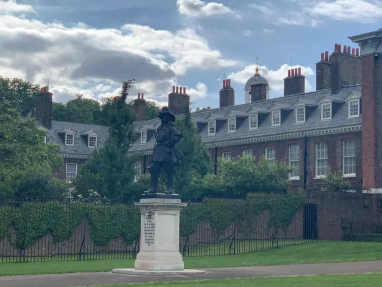 Ornate golden gates at Kensington Palace in London’s Hyde Park, featuring intricate black ironwork with gold detailing and royal crests. The grand entrance reflects the elegance and historic significance of the royal residence.
