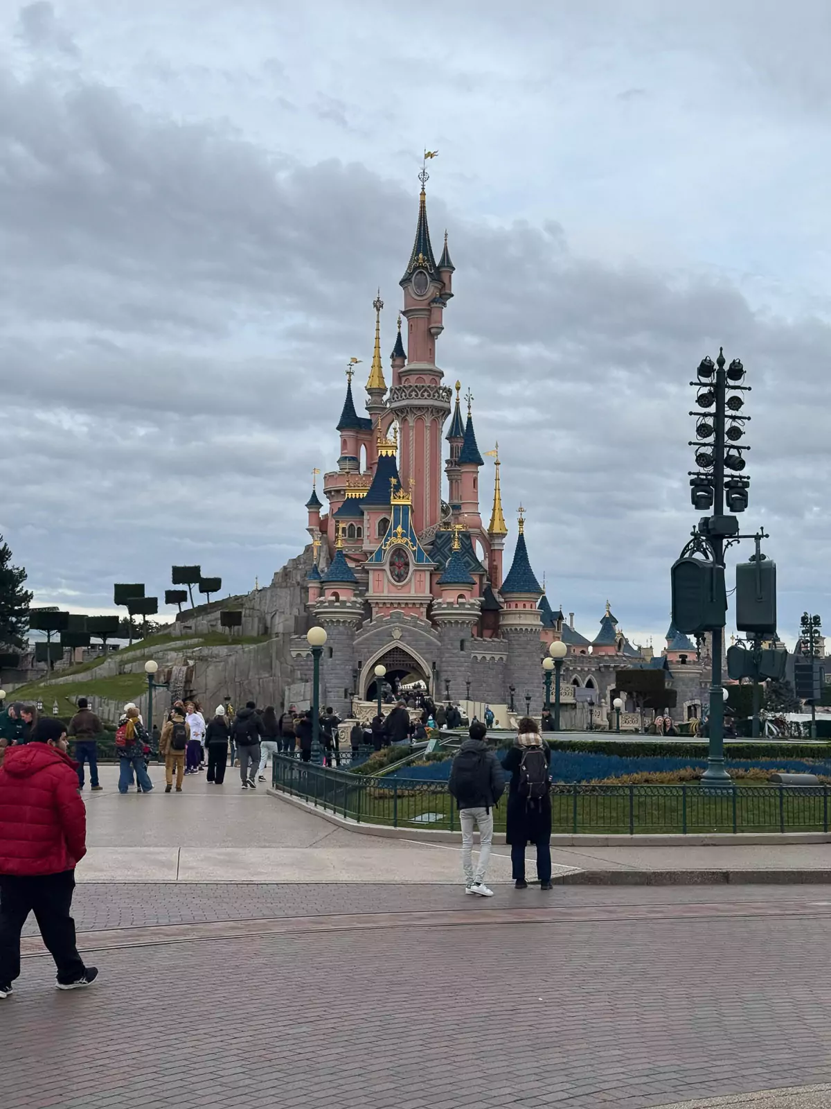 Sleeping Beauty’s Castle at Disneyland Paris, featuring its iconic pink towers, blue rooftops, and golden accents, standing proudly against a bright sky in the heart of the park.