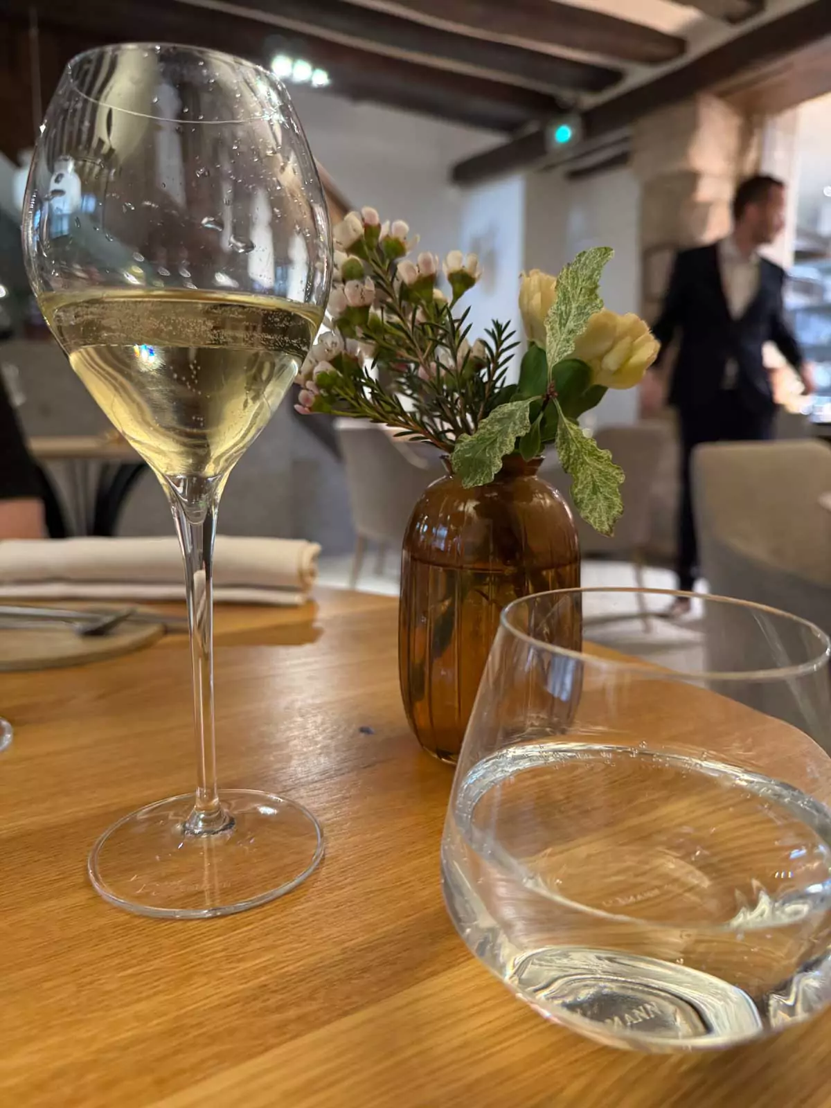 Glass of champagne on a table at Auberge Nicolas Flamel in Paris, France, with soft lighting and historic stone walls in the background, blending fine dining with centuries-old ambiance.