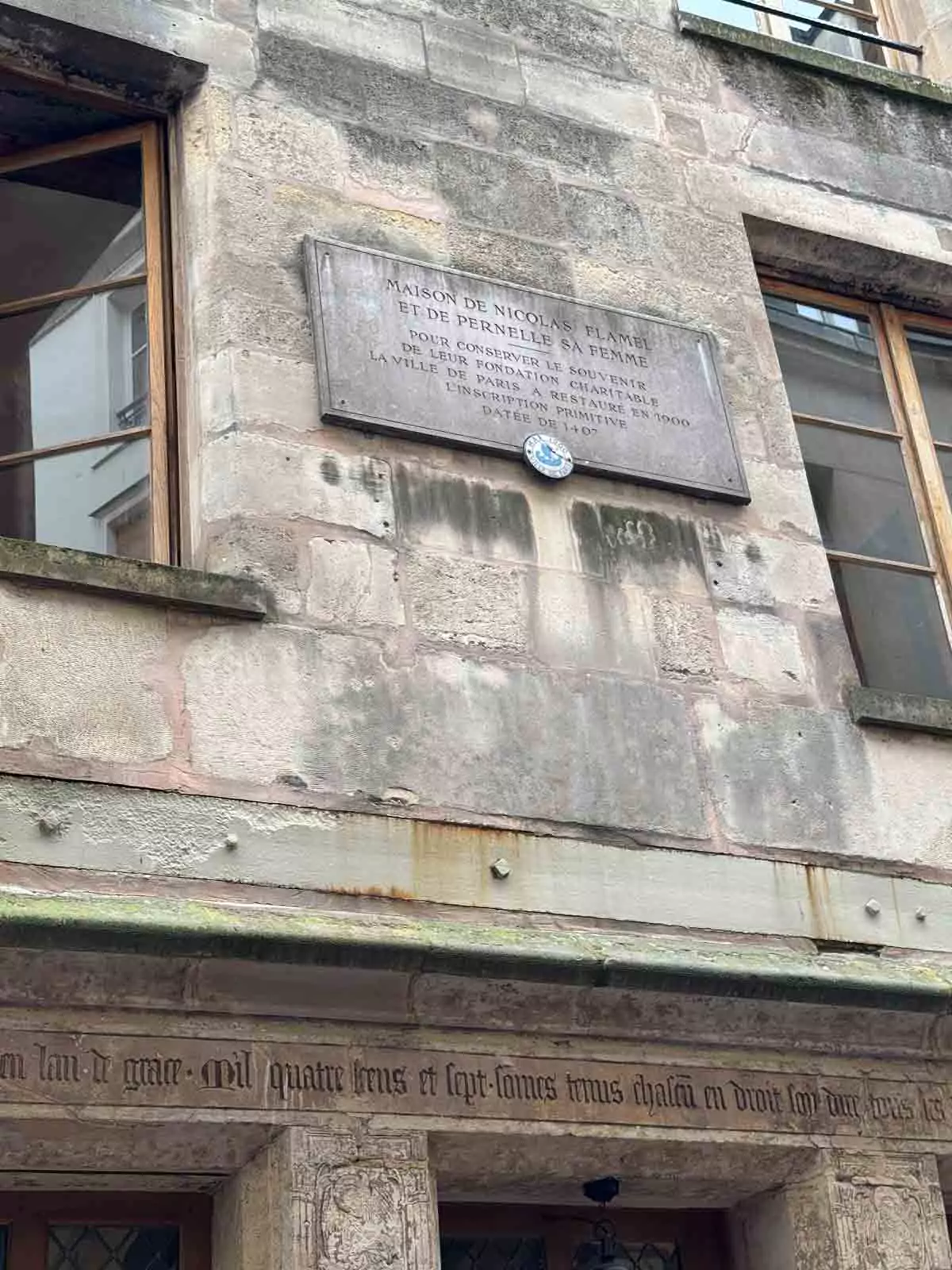 Exterior plaque on the façade of Auberge Nicolas Flamel in Paris, France, mounted on the historic stone wall, marking the building’s significance as one of the oldest surviving houses in the city.