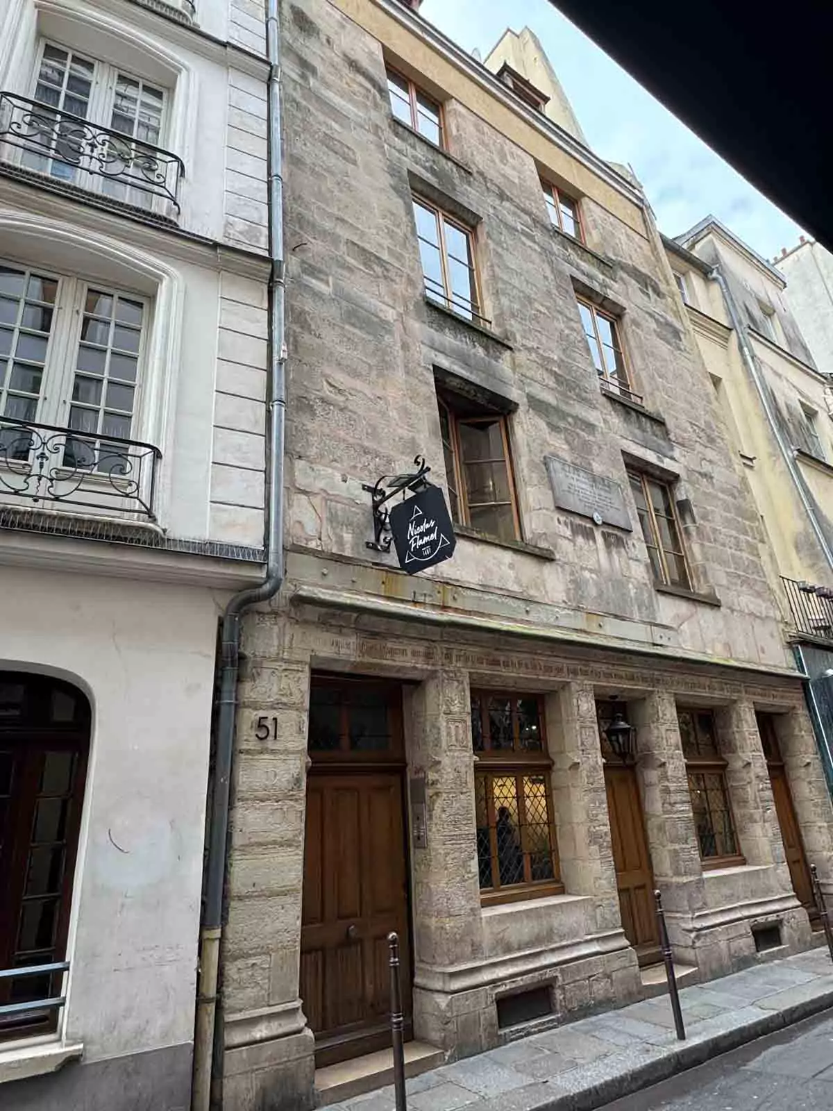 Exterior of Auberge Nicolas Flamel in Paris, France, one of the city’s oldest surviving buildings, featuring a stone façade with Gothic architectural details and a plaque marking its historic significance.