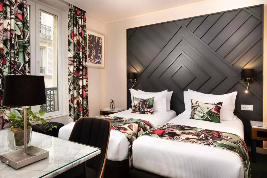 Boutique Hotels in Paris: Hotel des Arts in Montmartre, Paris, featuring a charming facade with French windows, wrought-iron balconies, and potted flowers. Nestled in the artistic Montmartre district, the boutique hotel exudes cozy Parisian elegance.