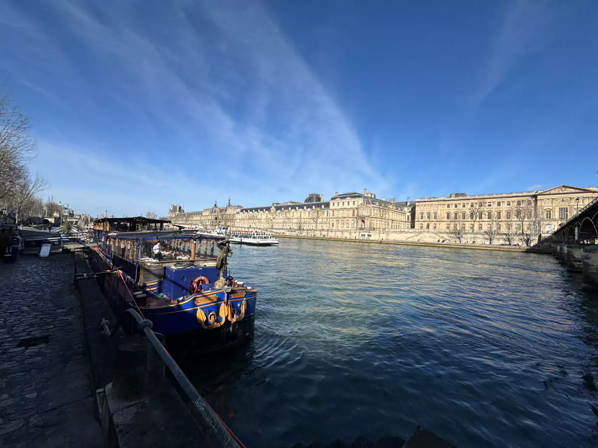 Lunch cruise aboard the blue Le Calife boat on the Seine River in Paris, with elegant table settings, panoramic windows, and views of Parisian landmarks drifting by — a scenic and relaxing experience