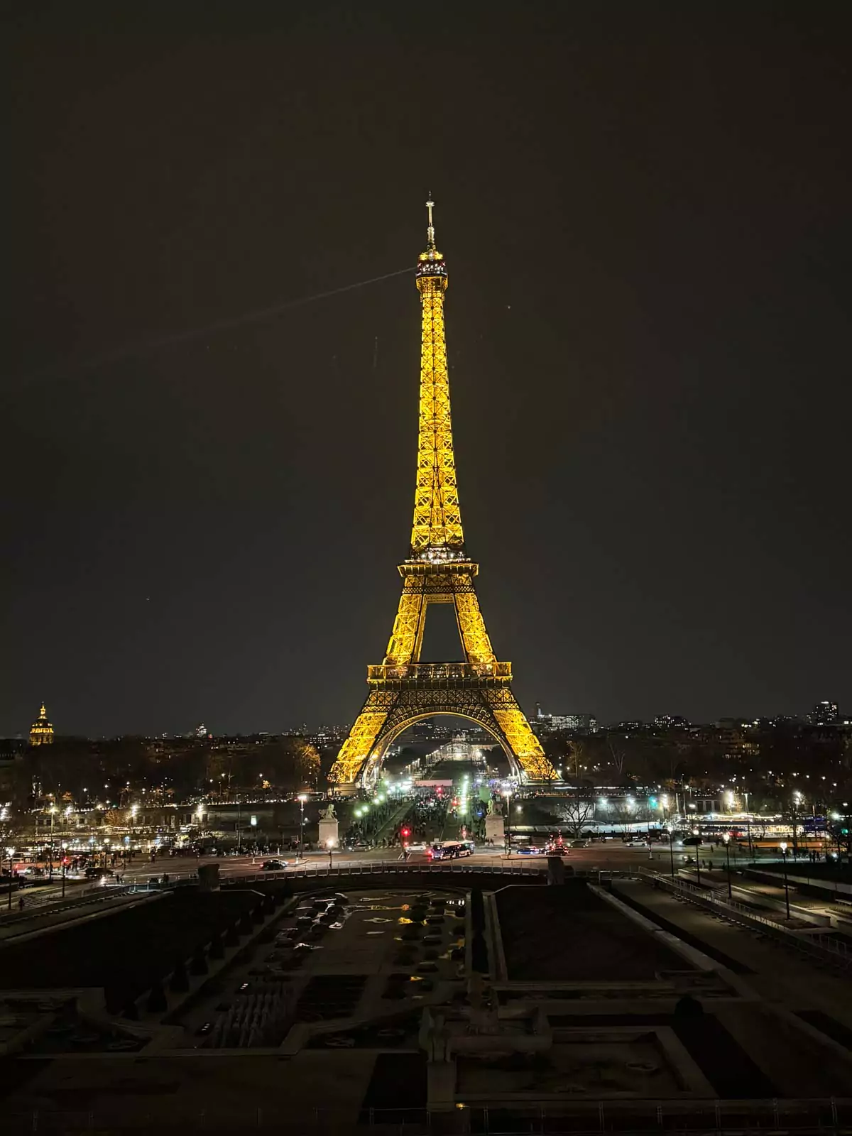 Eiffel Tower illuminated against the night sky in Paris, France, with golden lights glowing across its iron framework and a soft evening ambiance surrounding the landmark — a radiant view