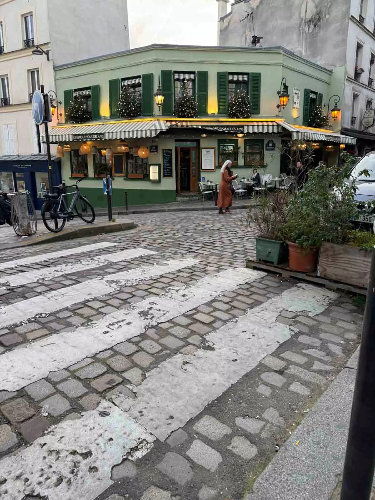 Scenic view of Montmartre in Paris, France, featuring charming cobblestone streets, classic Parisian buildings with wrought-iron balconies, and artists setting up easels in the square. The artistic atmosphere and hillside setting reflect the neighborhood’s bohemian spirit.