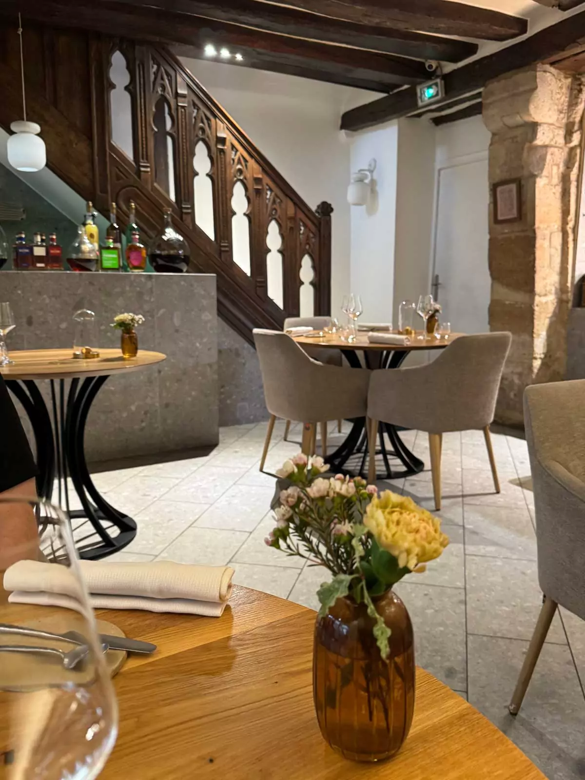Interior of Auberge Nicolas Flamel in Paris, France, with elegantly set dining tables, exposed stone walls, and intimate lighting that reflects the building’s 15th-century charm and modern fine dining atmosphere.