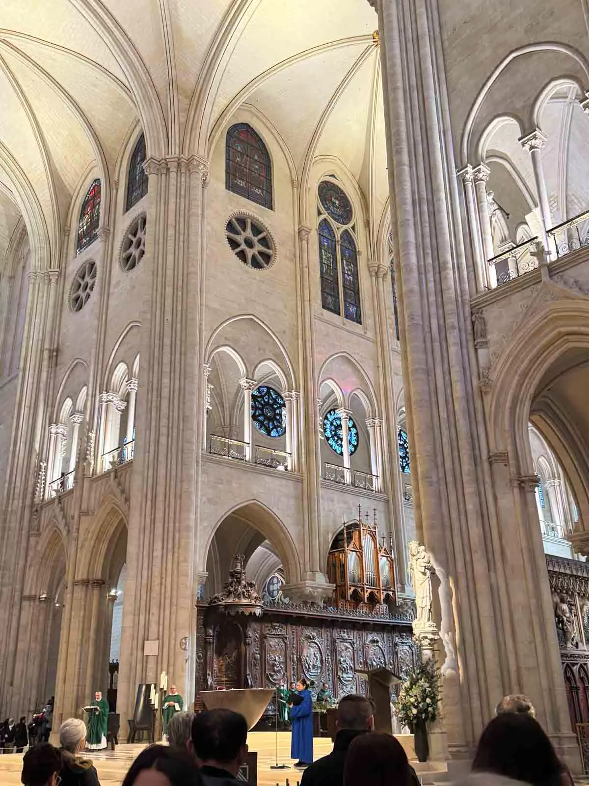 Altar of Notre-Dame Cathedral in Paris during mass, illuminated by soft candlelight and surrounded by gothic arches and ornate stone carvings. Clergy and worshippers participate in the sacred service, adding a solemn and reverent atmosphere to the historic space.