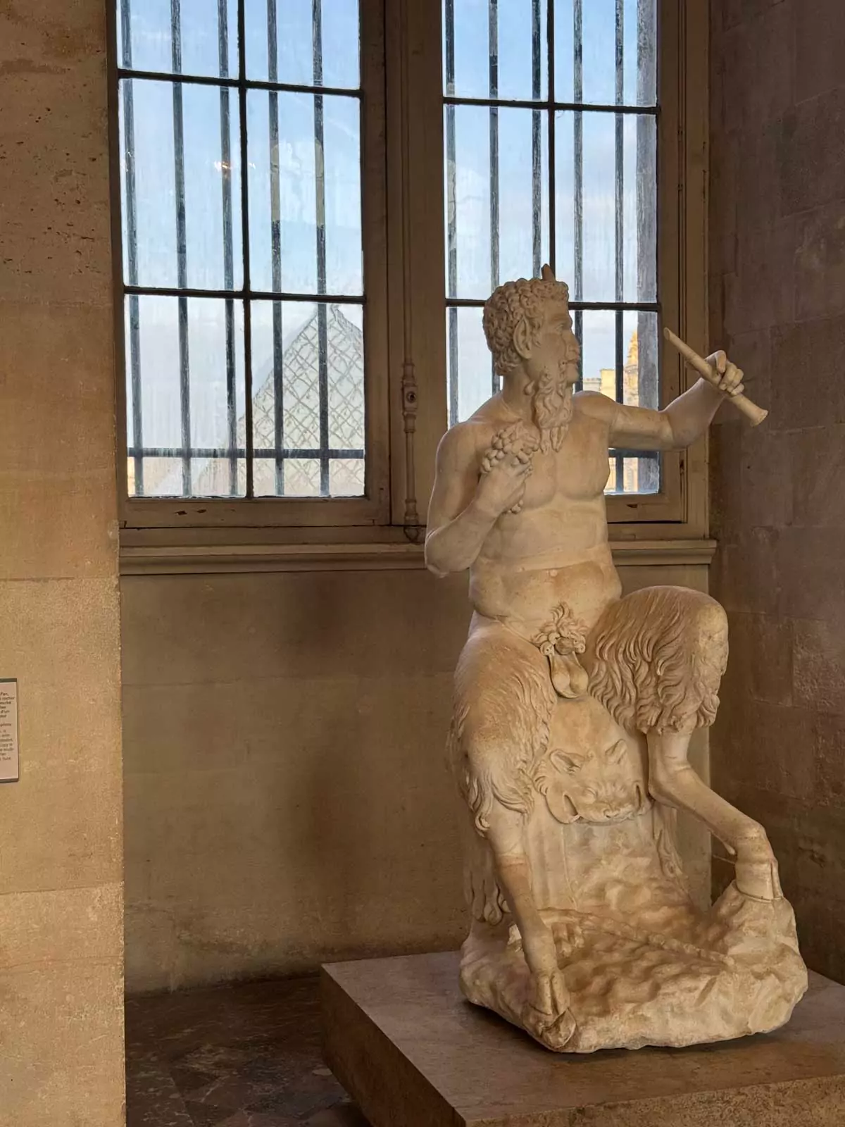 Ancient Greek sculpture of Pan and a youthful companion at the Louvre Museum in Paris, France, depicting mythological figures in motion with expressive detail and flowing form