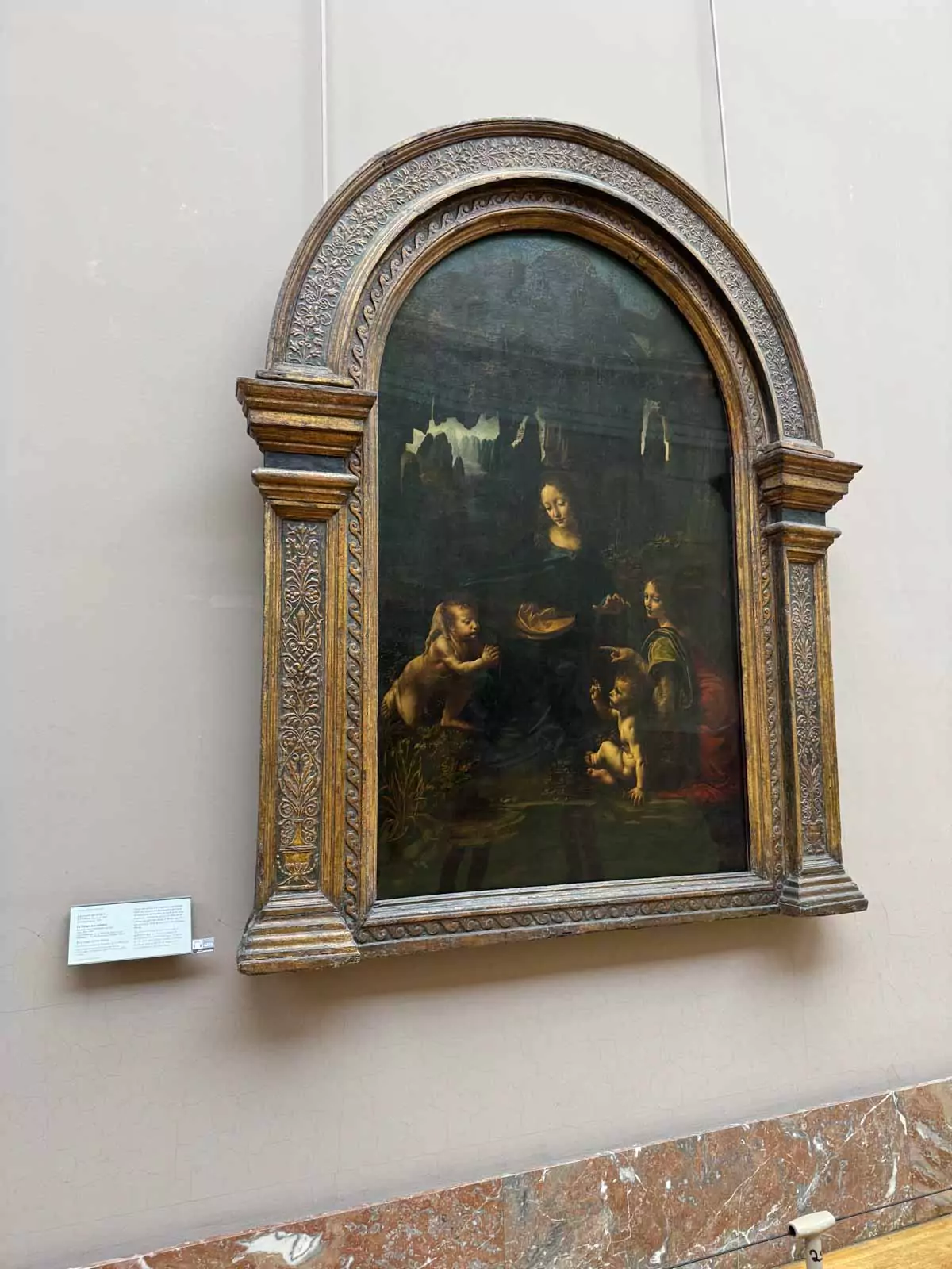 Leonardo da Vinci’s Virgin of the Rocks displayed at the Louvre Museum in Paris, France, featuring the Virgin Mary, Christ Child, John the Baptist, and an angel set within a rocky grotto — a Renaissance masterpiece