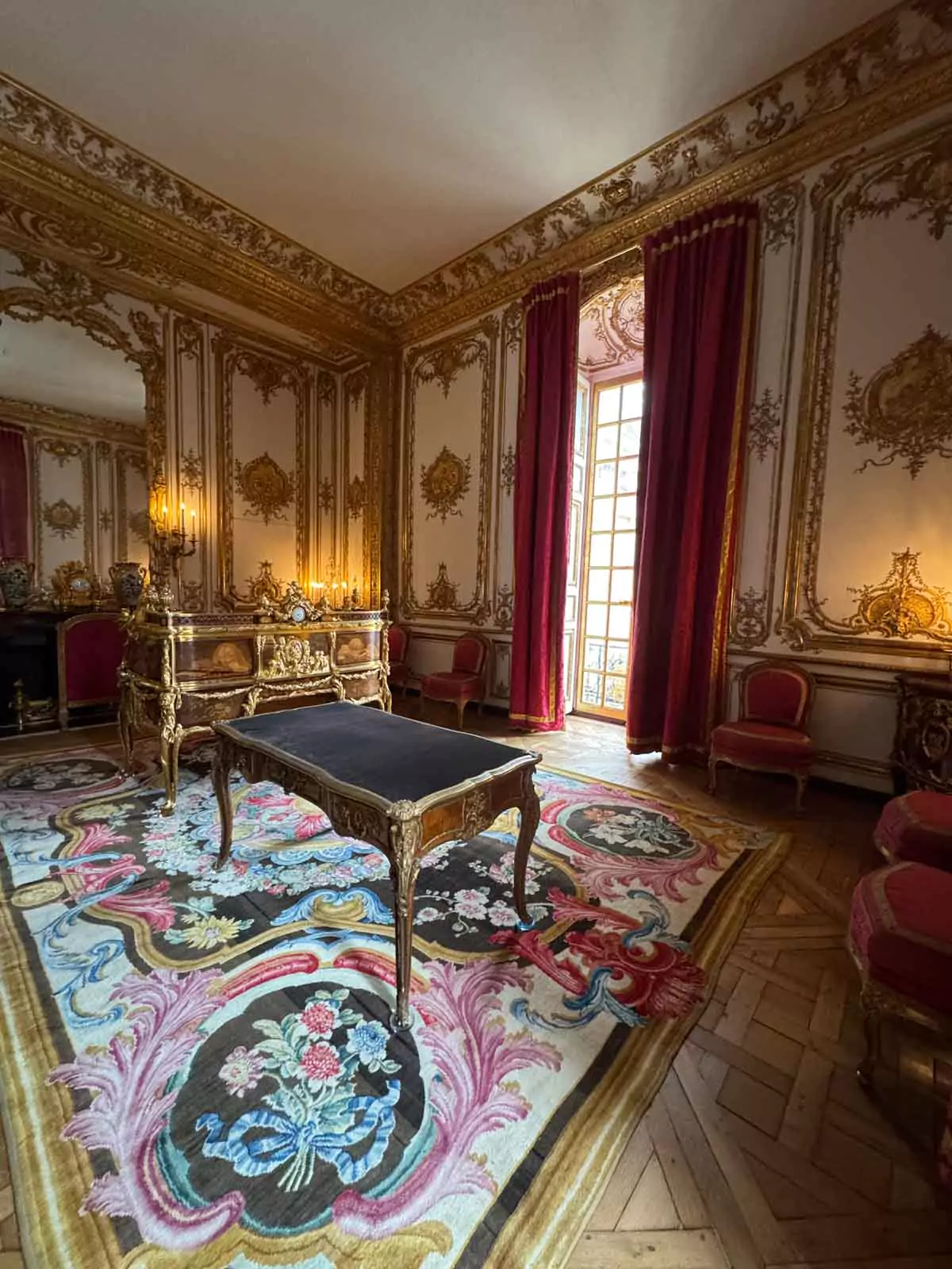 The Cabinet Intérieur, or King’s Study, at the Palace of Versailles, featuring an ornate writing desk, gilded moldings, rich wood paneling, and royal blue accents
