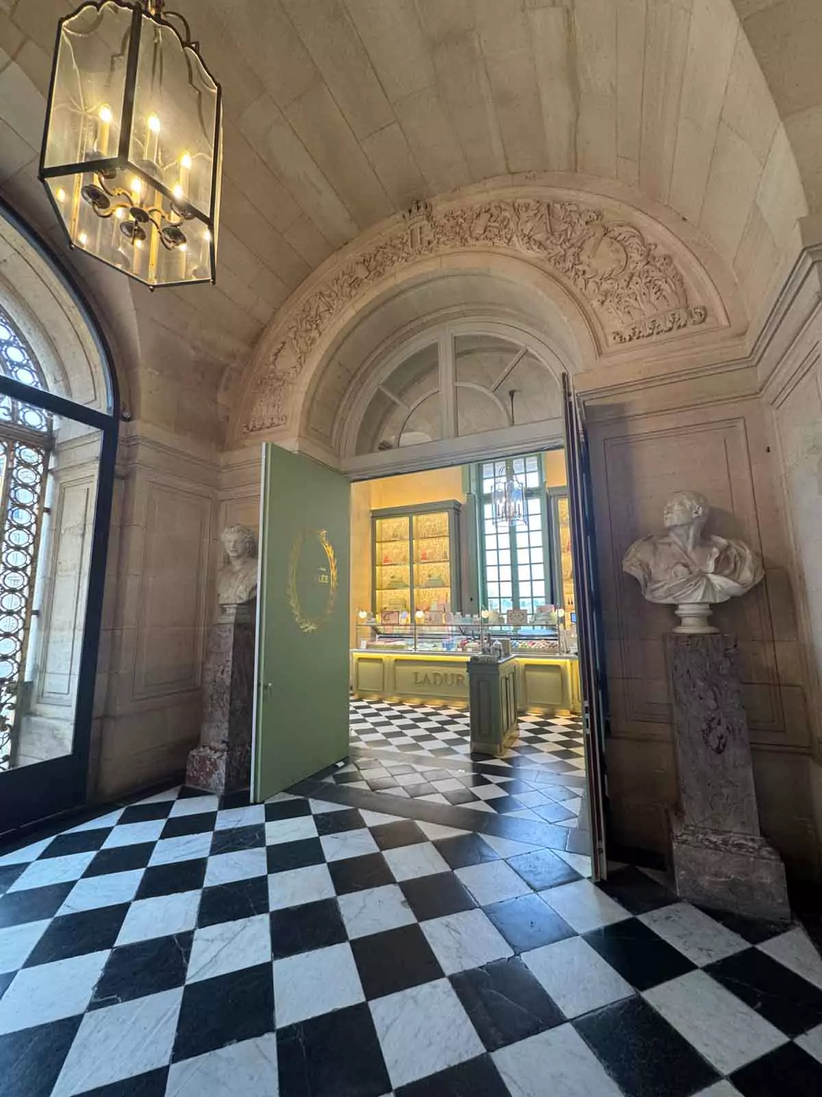 The Ladurée store at Versailles, featuring a charming boutique exterior with pastel signage and window displays filled with colorful macarons and elegant packaging