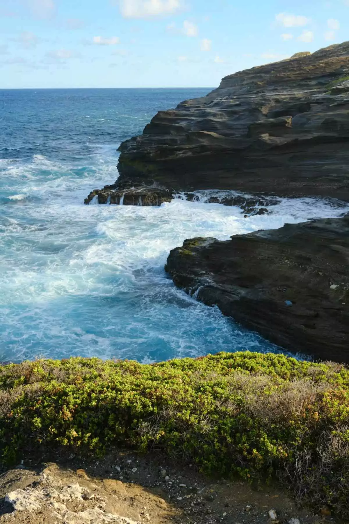 Garden of the Gods (Keahiakawelo) on Lāna‘i, a surreal landscape of red rock formations, boulders, and dusty terrain set against a dramatic sky and distant ocean views.