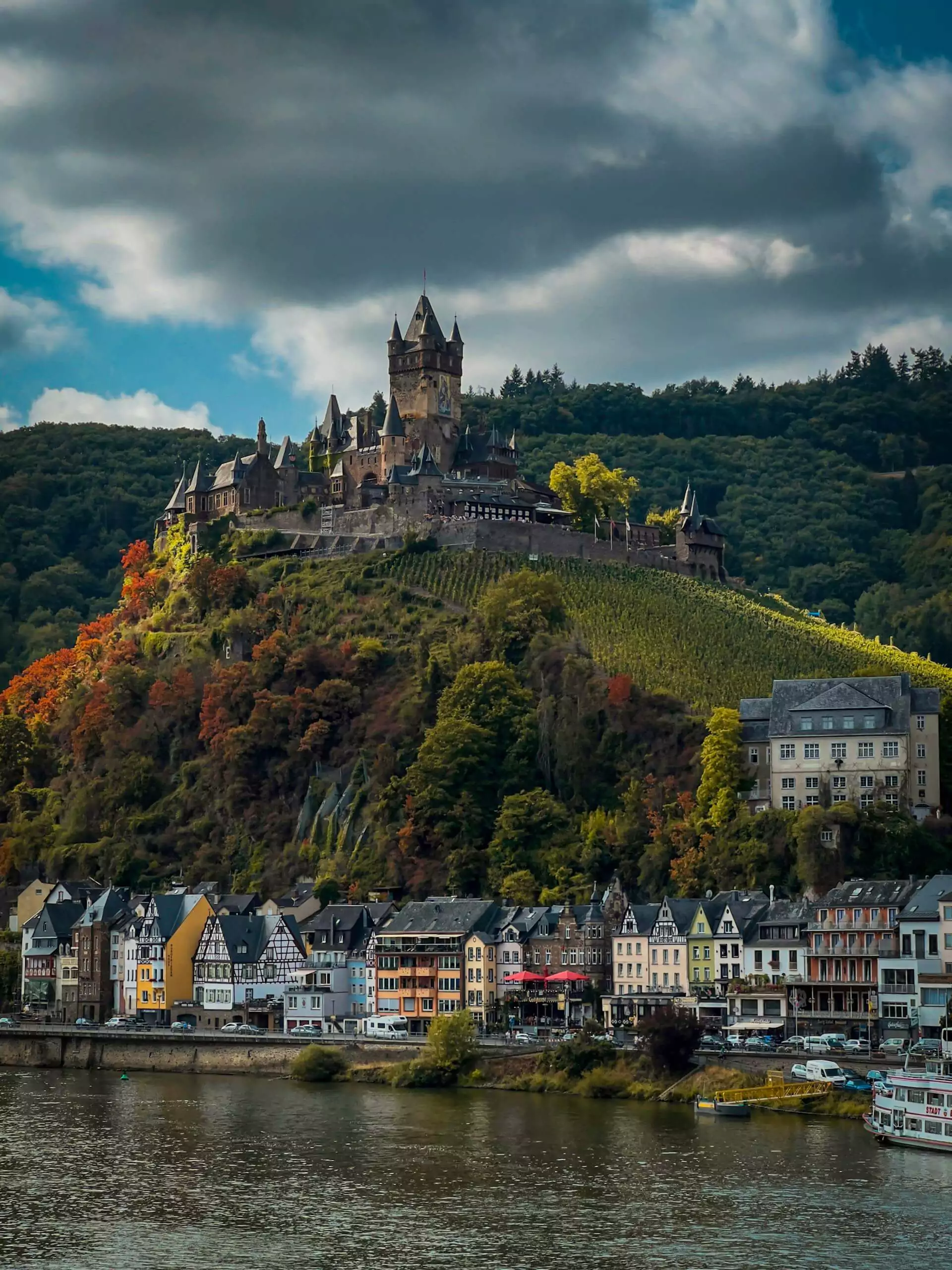 Cochem Castle in Germany, a hilltop fortress overlooking the Moselle River, featuring Gothic Revival towers and turrets surrounded by vineyards and medieval townhouses.