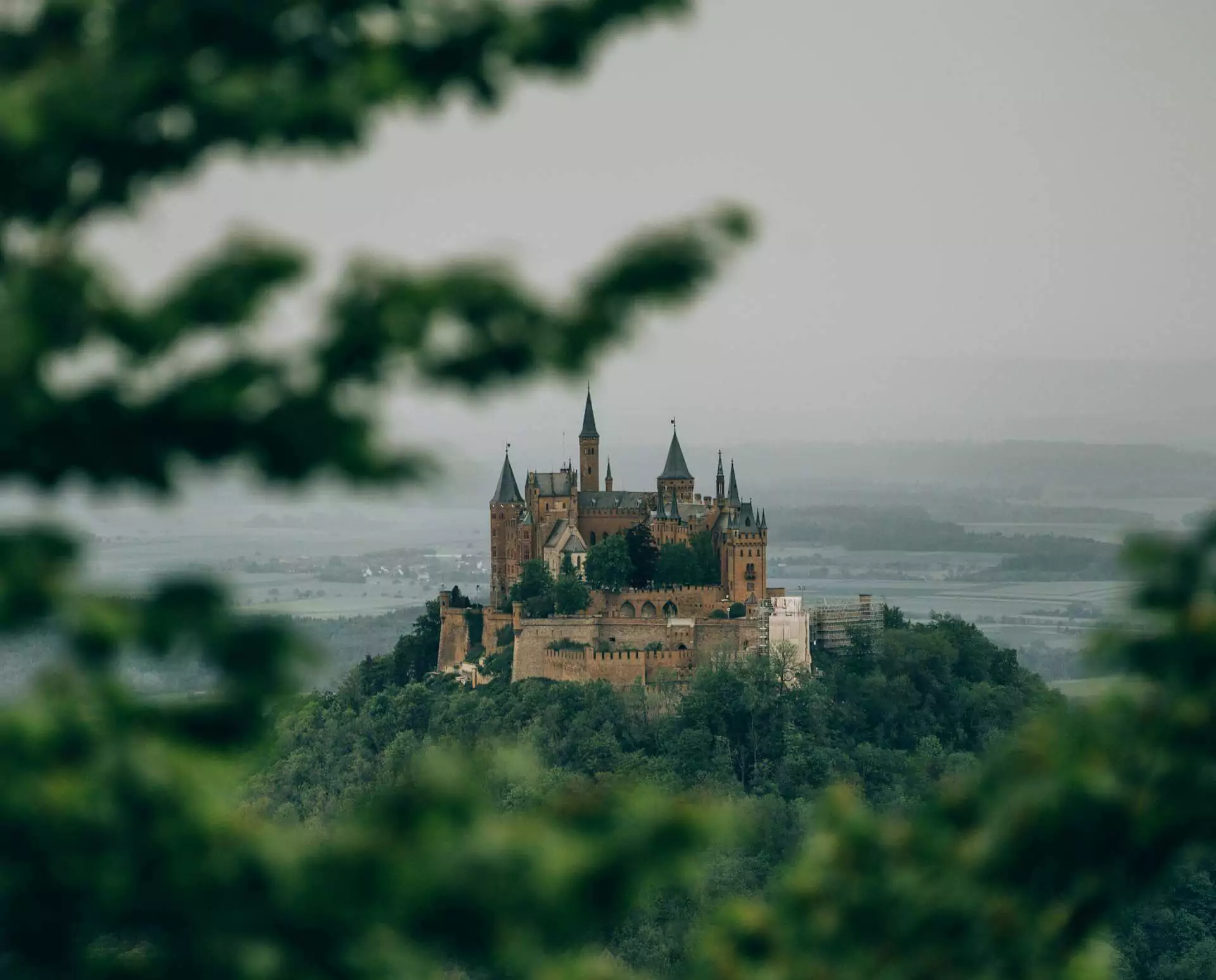 Hohenzollern Castle in Germany, perched atop a forested hill with pointed towers, stone walls, and panoramic views, resembling a storybook fortress and reflecting its Prussian royal heritage.