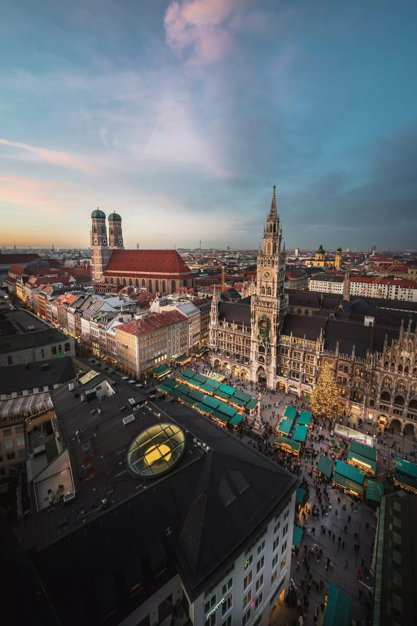 Aerial view of Marienplatz in Munich, Germany, showcasing the New Town Hall with its Gothic Revival façade, the central square bustling with people, and red-roofed buildings surrounding the historic city center.