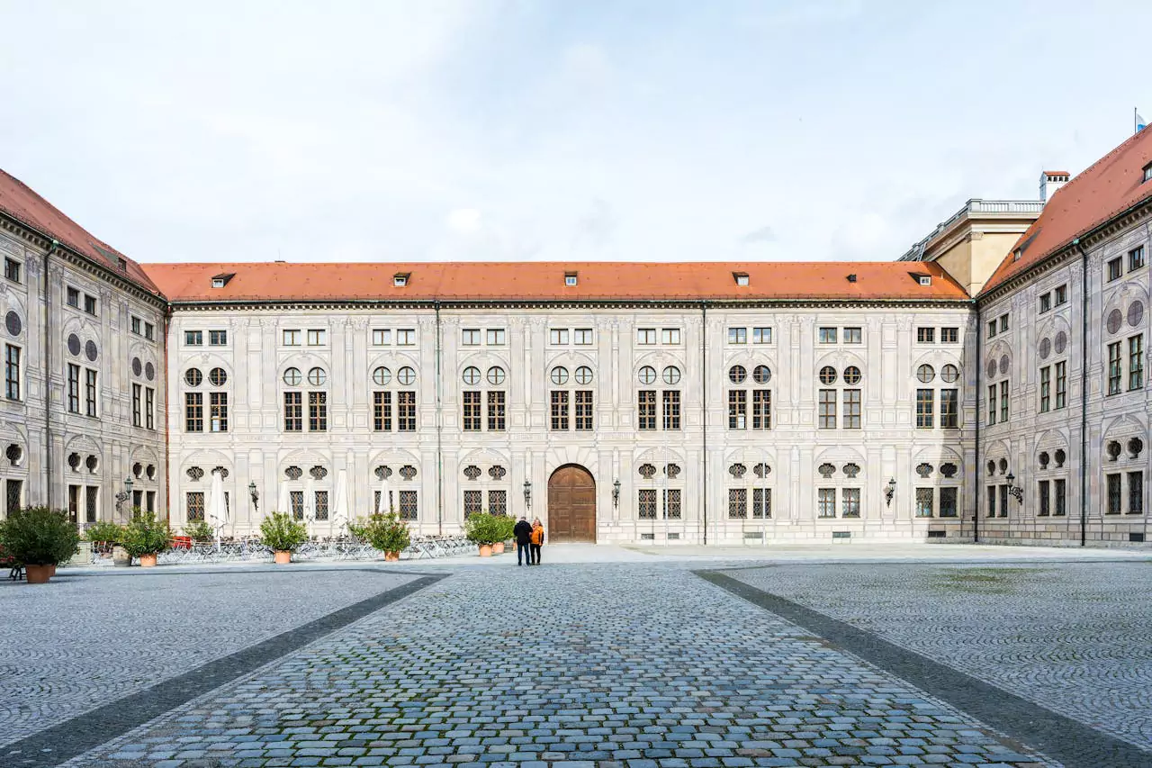 Exterior of the Residenz in Munich, Germany, showcasing its grand Renaissance and Baroque-style façade with arched windows, stone detailing, and a spacious courtyard entrance to the former royal palace.