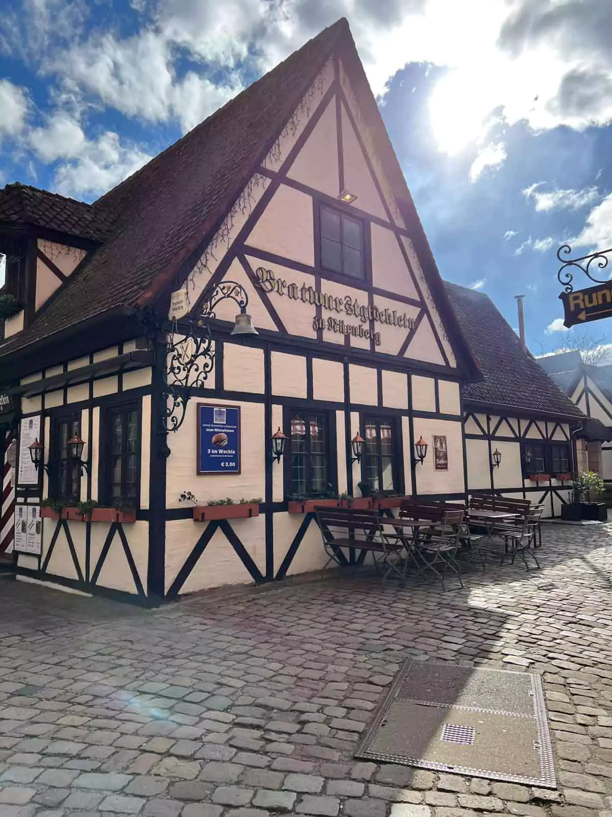The traditional Bratwurstglöcklein restaurant exterior, featuring rustic timber framing and a charming sign above the entrance. The historic building invites visitors to enjoy classic German cuisine in a cozy setting.