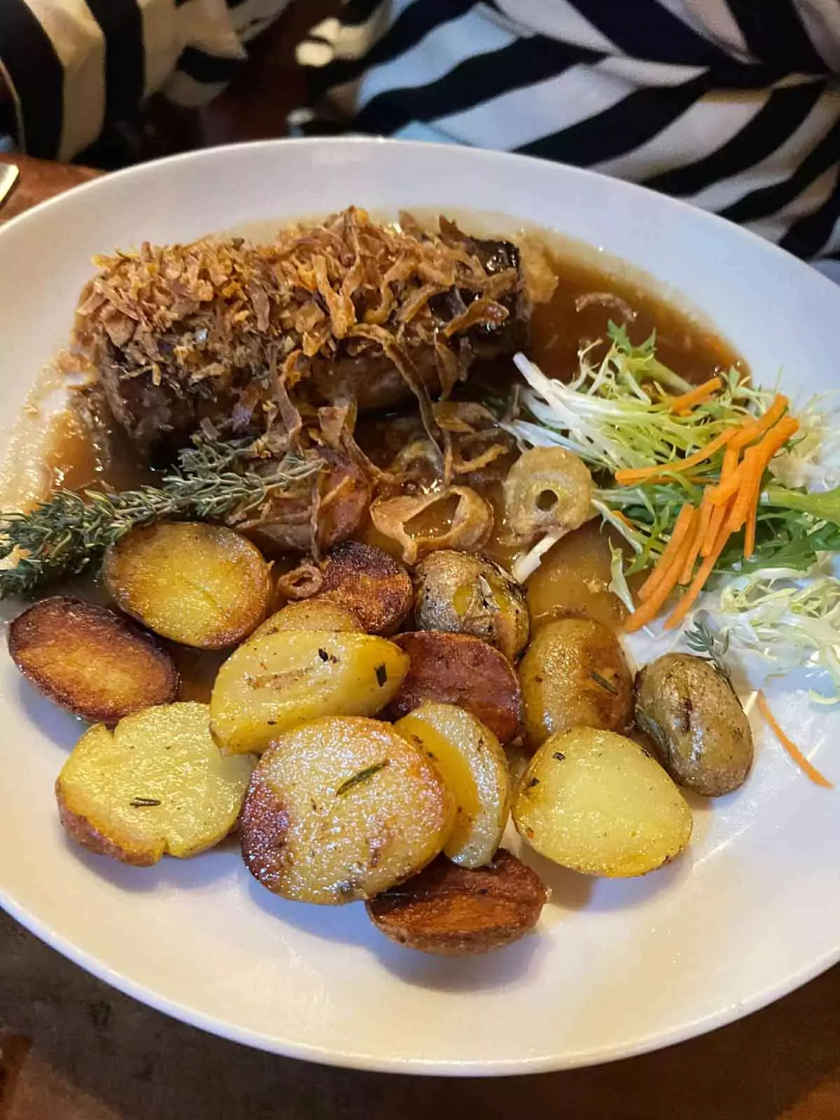 Plate of hearty food at Im Keller, featuring roasted potatoes alongside a savory main dish, served on rustic dinnerware in a cozy, traditional setting — a comforting meal