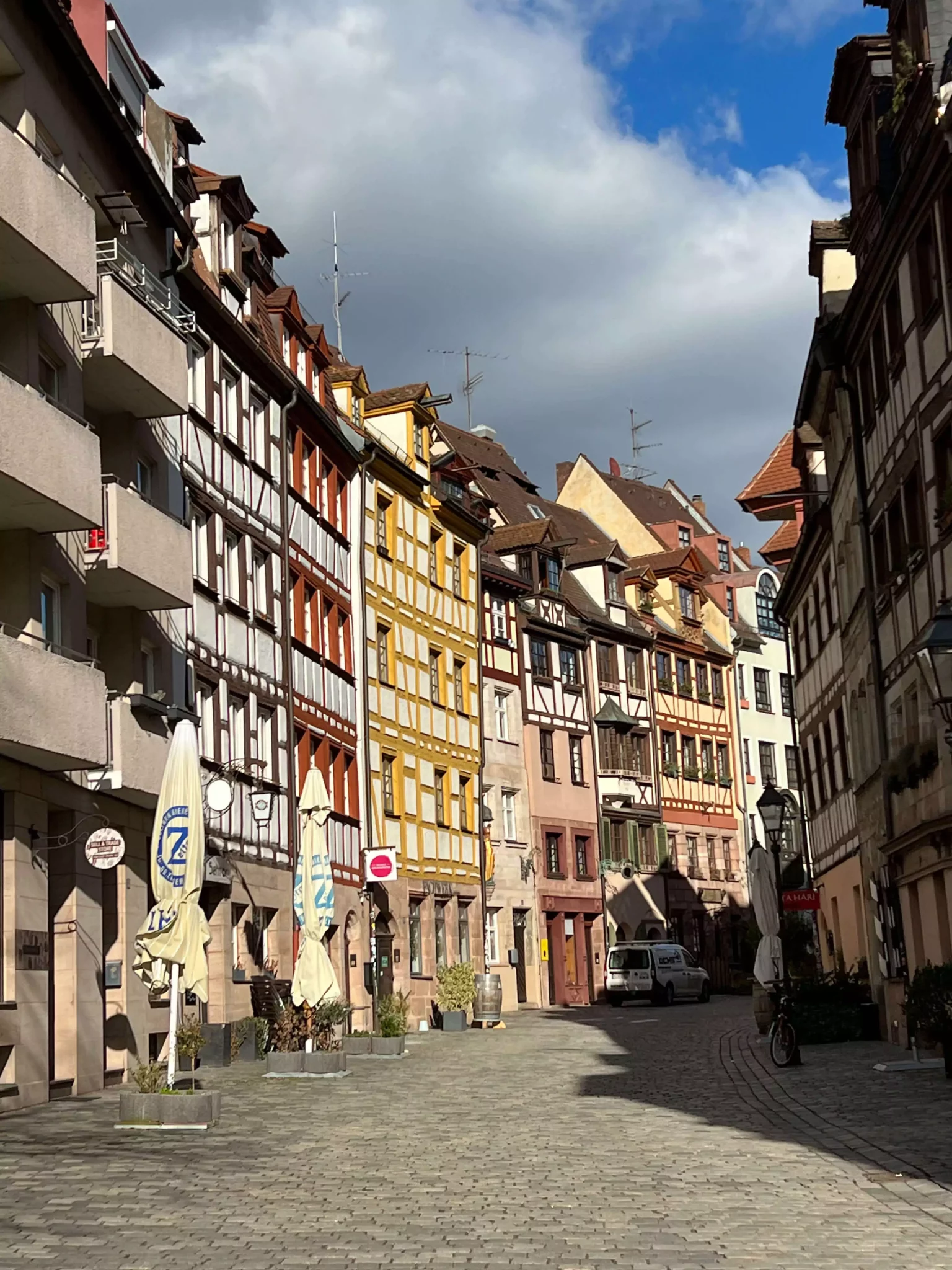 A charming street view of Weißgerbergasse, also known as Tanner’s Lane, lined with colorful half-timbered houses featuring steep roofs and flower boxes. The historic lane reflects traditional Bavarian architecture in Nuremberg.