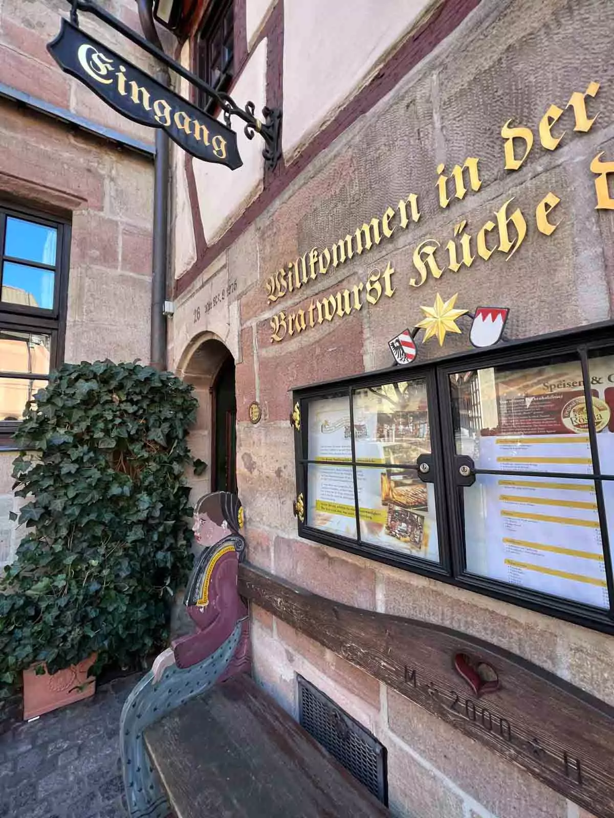 Entrance to Zum Gulden Stern, the historic bratwurst restaurant in Nuremberg, Germany, with its traditional timber-framed exterior, arched doorway, and vintage signage