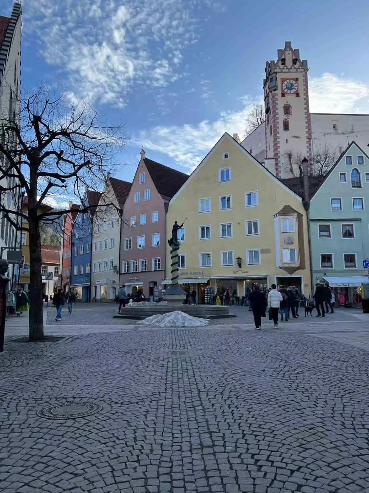 Row of colorful historic buildings in Füssen, Germany, with pastel facades, painted details, and alpine-style architecture lining a charming cobblestone street.