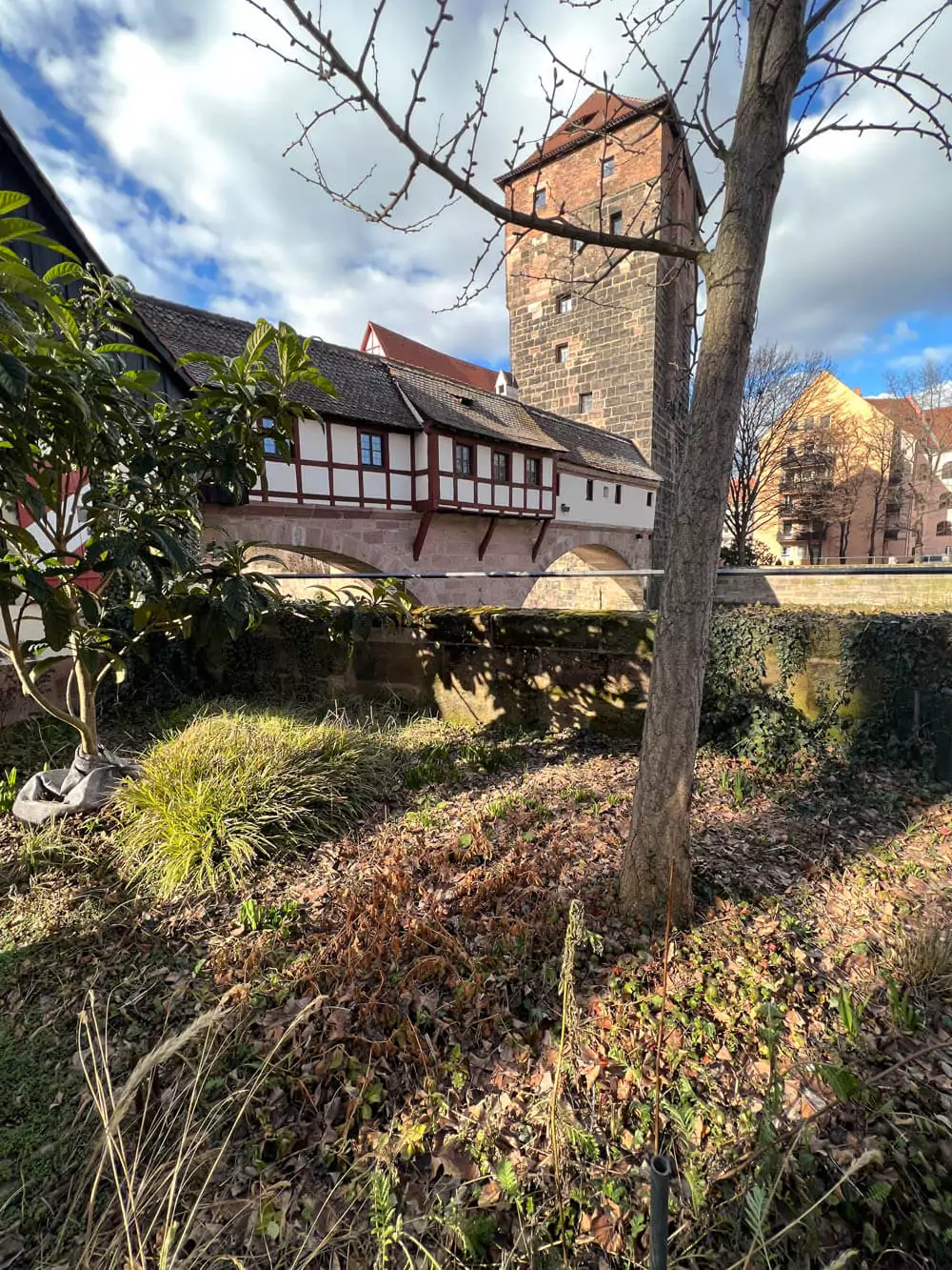 Weinstadel in Nuremberg, a historic half-timbered building by the Pegnitz River, reflected in the water alongside the Henkersteg footbridge and medieval towers.