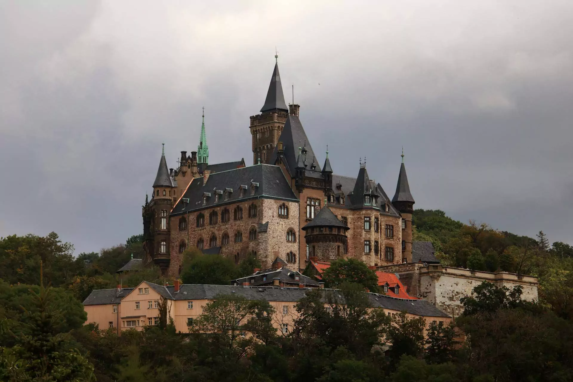 Wernigerode Castle in Germany, perched on a forested hill above the Harz region, with fairy-tale spires, half-timbered sections, and panoramic views of the town below.