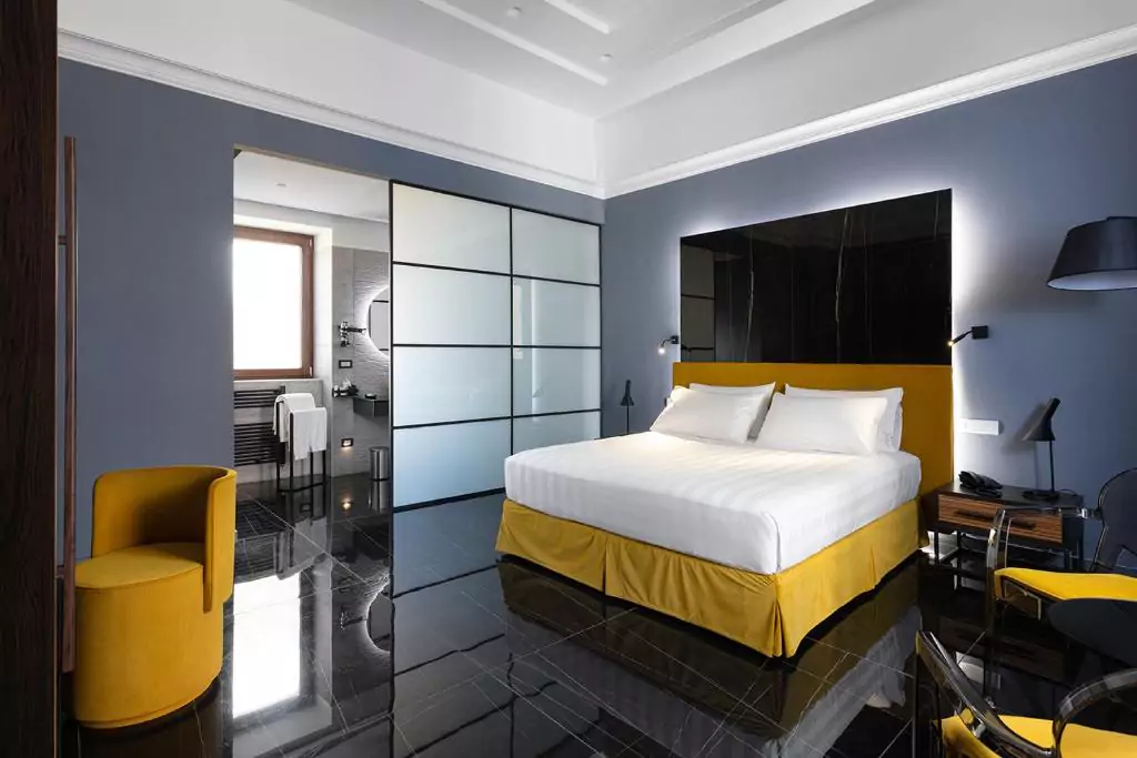 Hotel Poerio in Naples, Italy, showcasing a stylish boutique room with contemporary furnishings, soft lighting, and a comfortable bed, located in the elegant Chiaia neighborhood