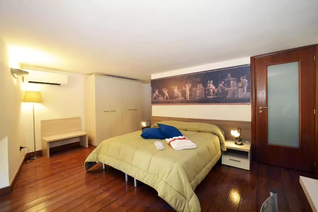View of the bedroom at Italia Apartment, featuring a neatly made bed with neutral linens, soft lighting, and minimalist decor in a cozy, modern setting — a peaceful retreat