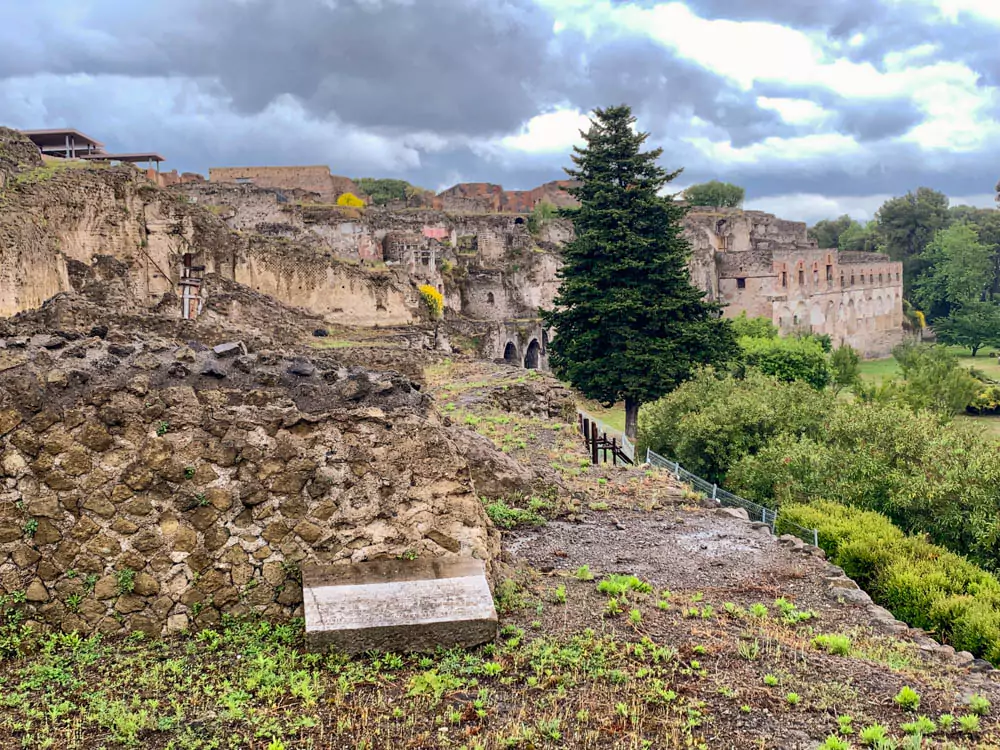 Ruins in Regio VIII, Insula of the Archaeological Park of Pompeii, Italy, featuring weathered stone walls, partial columns, and ancient pathways that reveal the layout of Roman homes and shops.